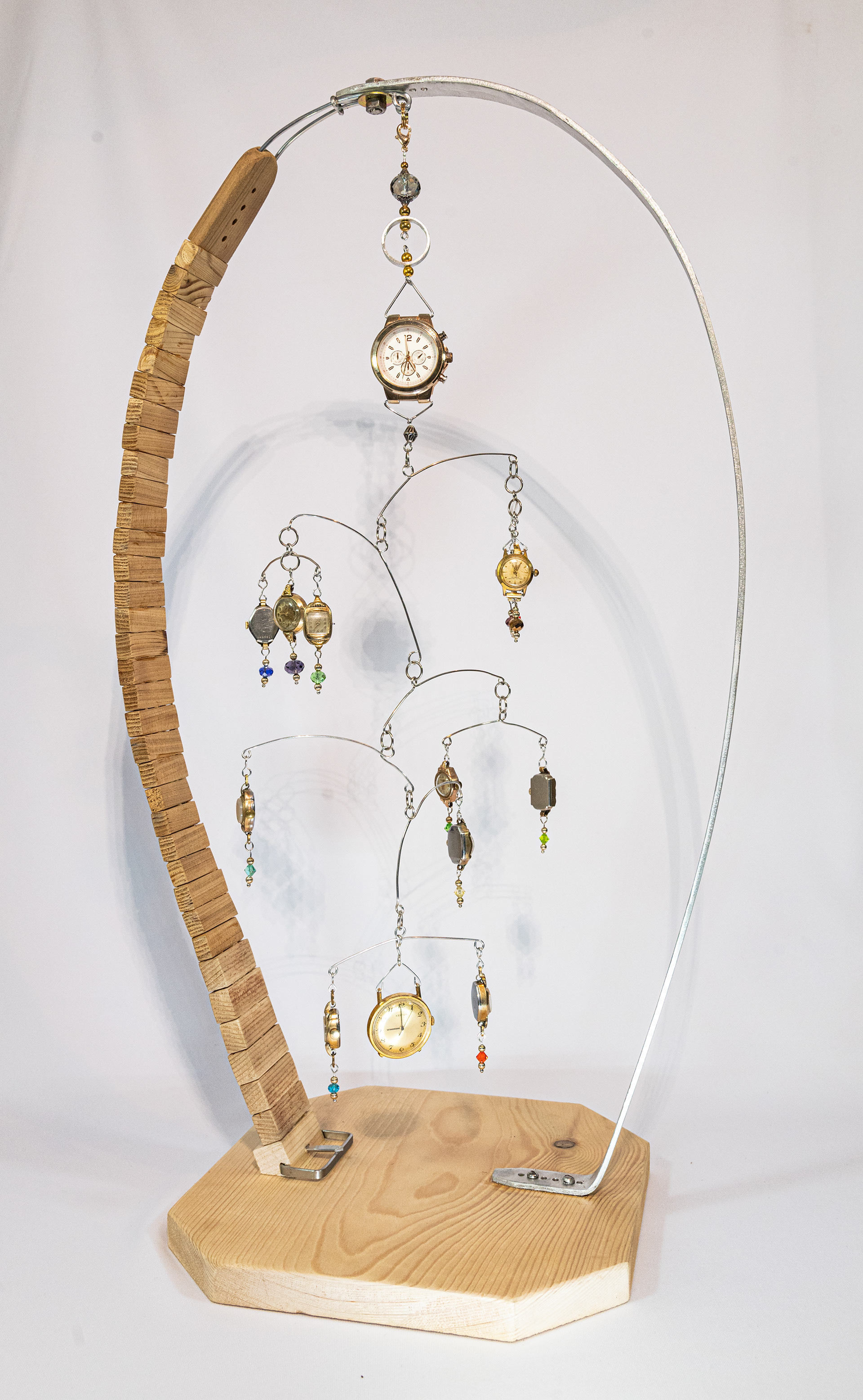 "9 to 5" is part mobile and part stabile,  a composite of vintage watch faces. They hang and rotate with the slightest breeze. The top watch is set at 9am, time changes as you gaze down to the bottom watch which is set at 5pm. Made with aluminum hand formed wire, a collection of vintage watches, metal findings on a base of fir and aluminum. 13 inches wide x 9 inches deep and 23 inches high, $175