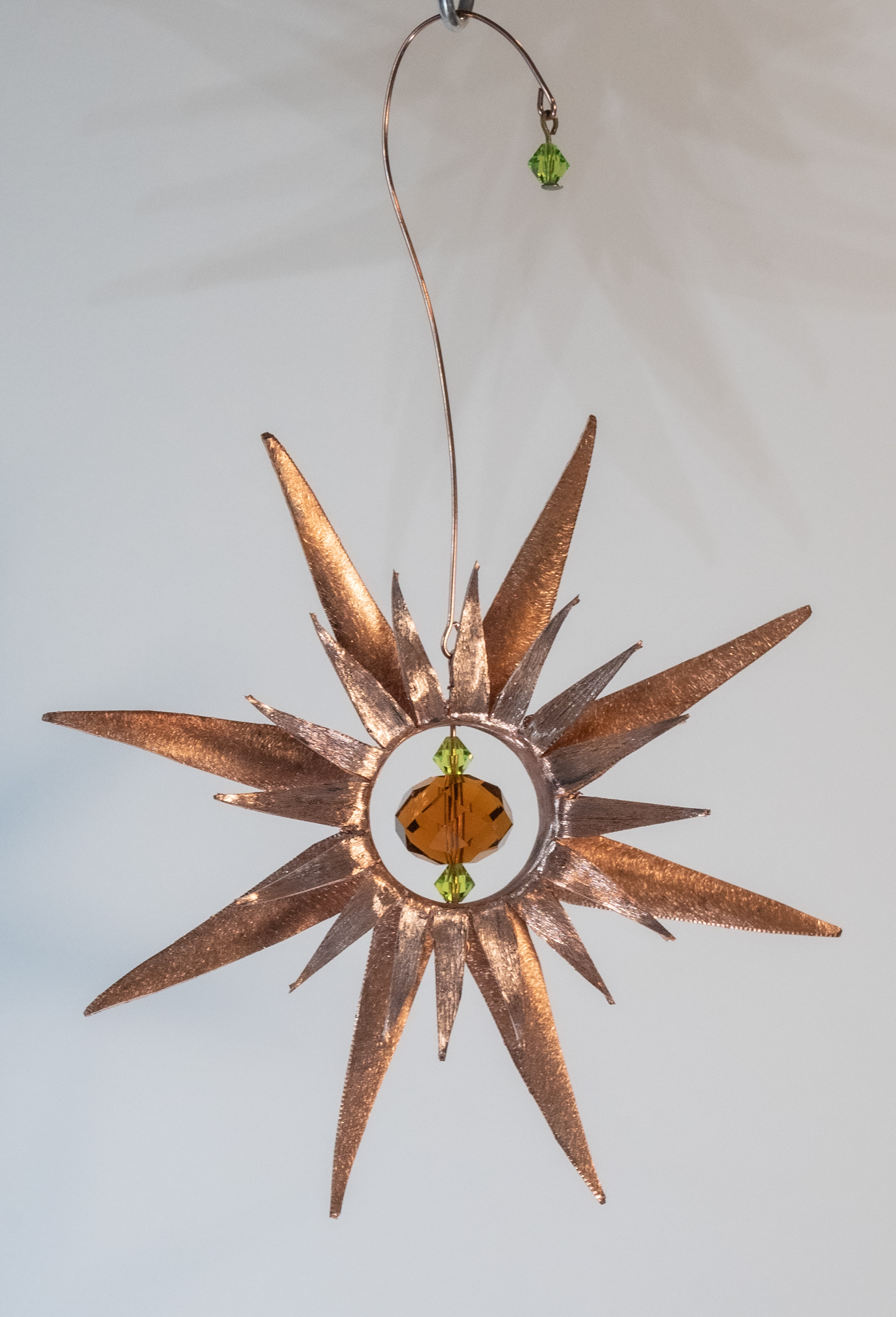 "Far Out"  is a handcut and shaped copper flower with an amber and green glass crystal centre, $75
