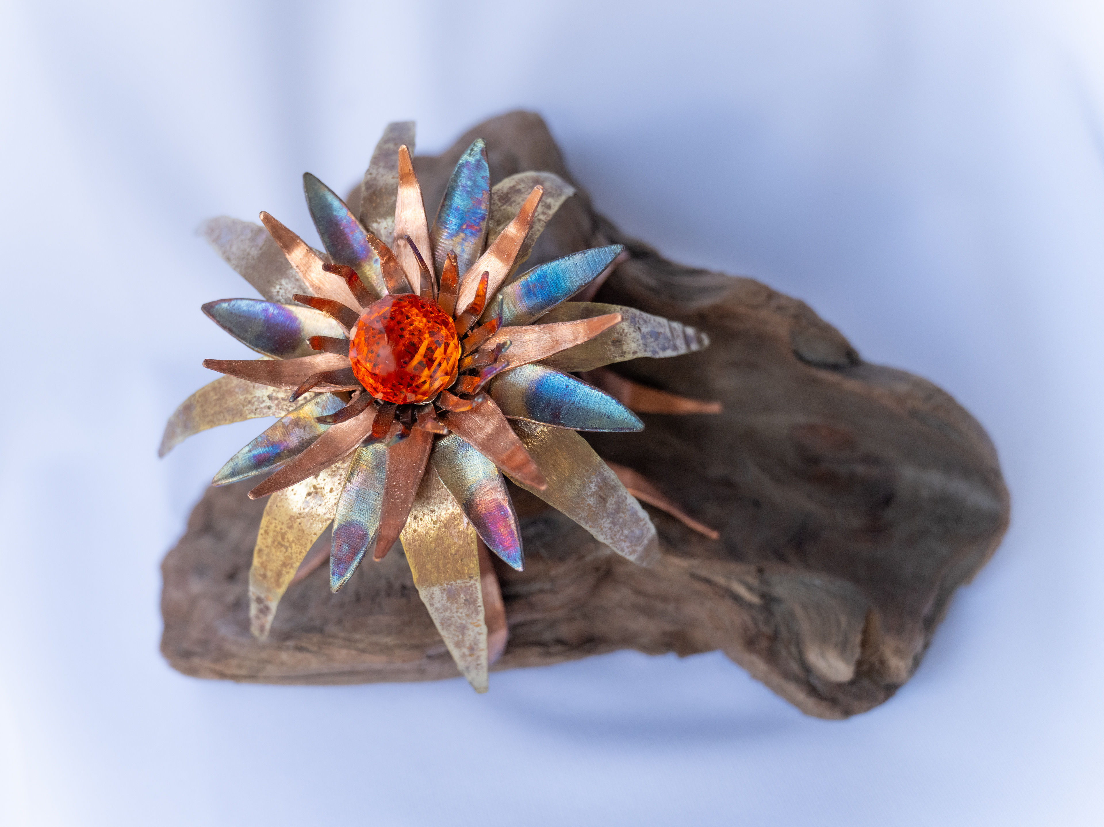 "Madeleine",  8.5 x 6 x 5.25, has a copper and brass flower with an orange crystal centre and is mounted on Vancouver Island driftwood, $175
