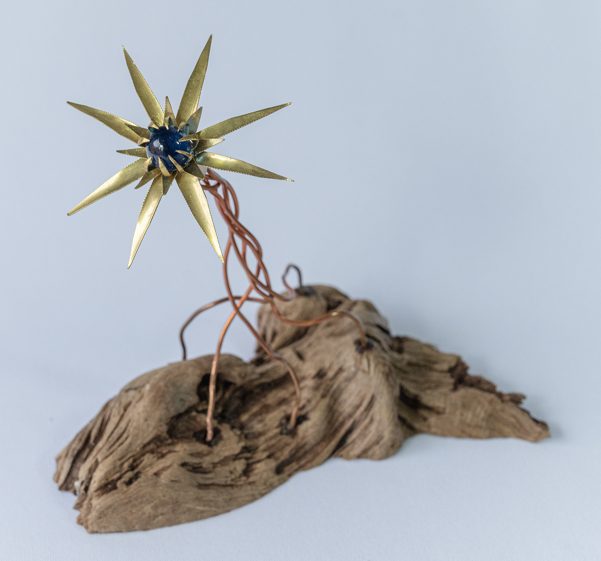 "Alien Flower" is a hand cut and shaped brass flower with a glass marble centre and copper wire set into Vancouver Island driftwood  6.5 inches wide x 6 high x 4.25 deep, $75