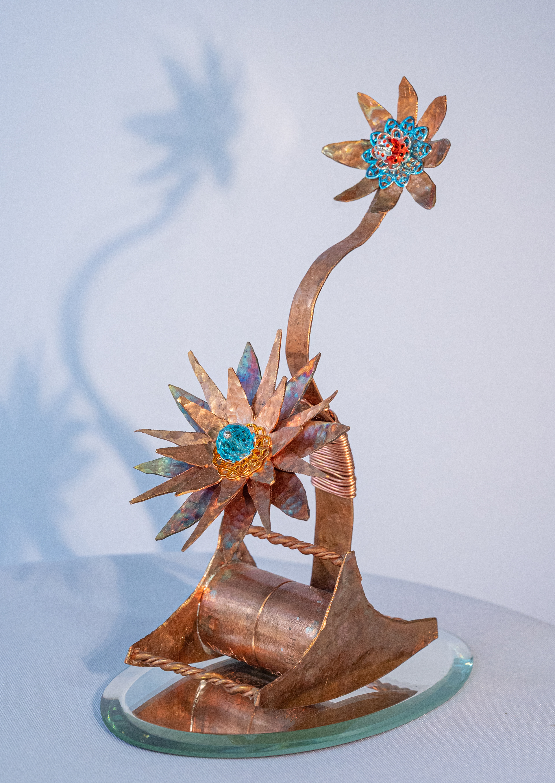 "Tipsy" features copper flowers with blue and red accents on a copper rocking base, 6 inches high x  2.5 inches wide x 3.25 inches deep, $75