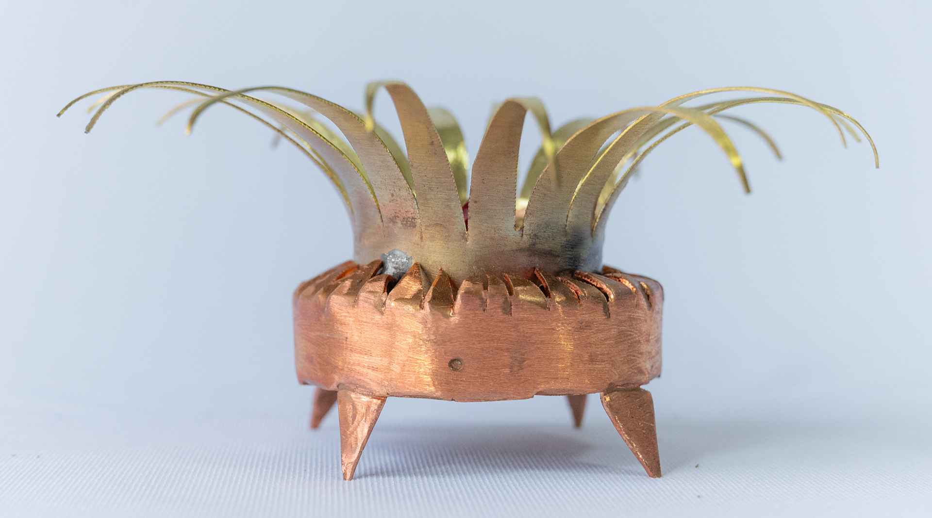 "A Star is Born", 4.75 inches in diameter x 2.25 inches high. Made of hand cut and shaped copper and brass with a red glass crystal heart. Side view, $75