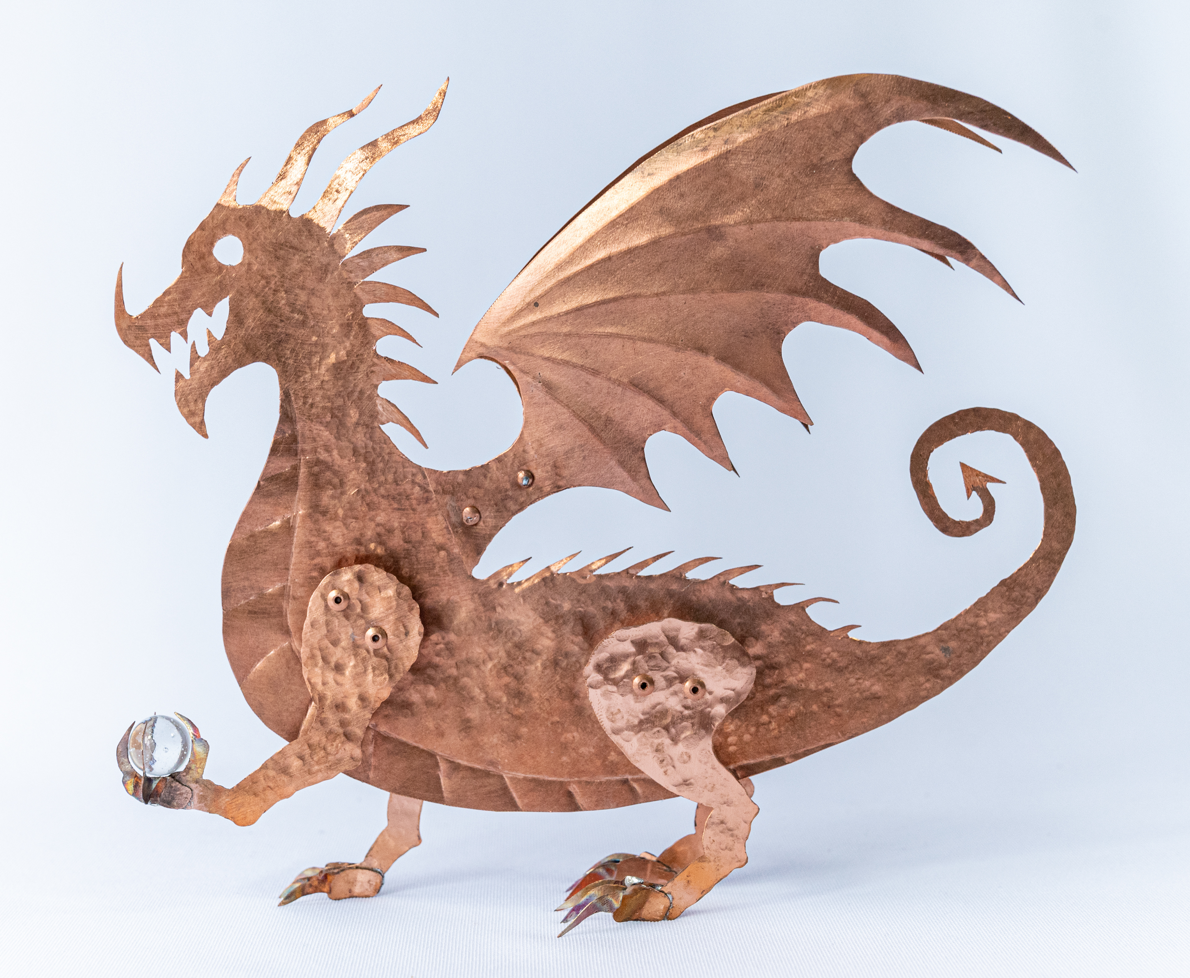 This amazing one of a kind Dragon is a unique and original design by Marty Borsboom. Hand cut from a sheet of copper, it is hand hammered and embossed and holds a glass marble. It stands at 9 inches high  x 7.5 wide and 2 inches deep. $175