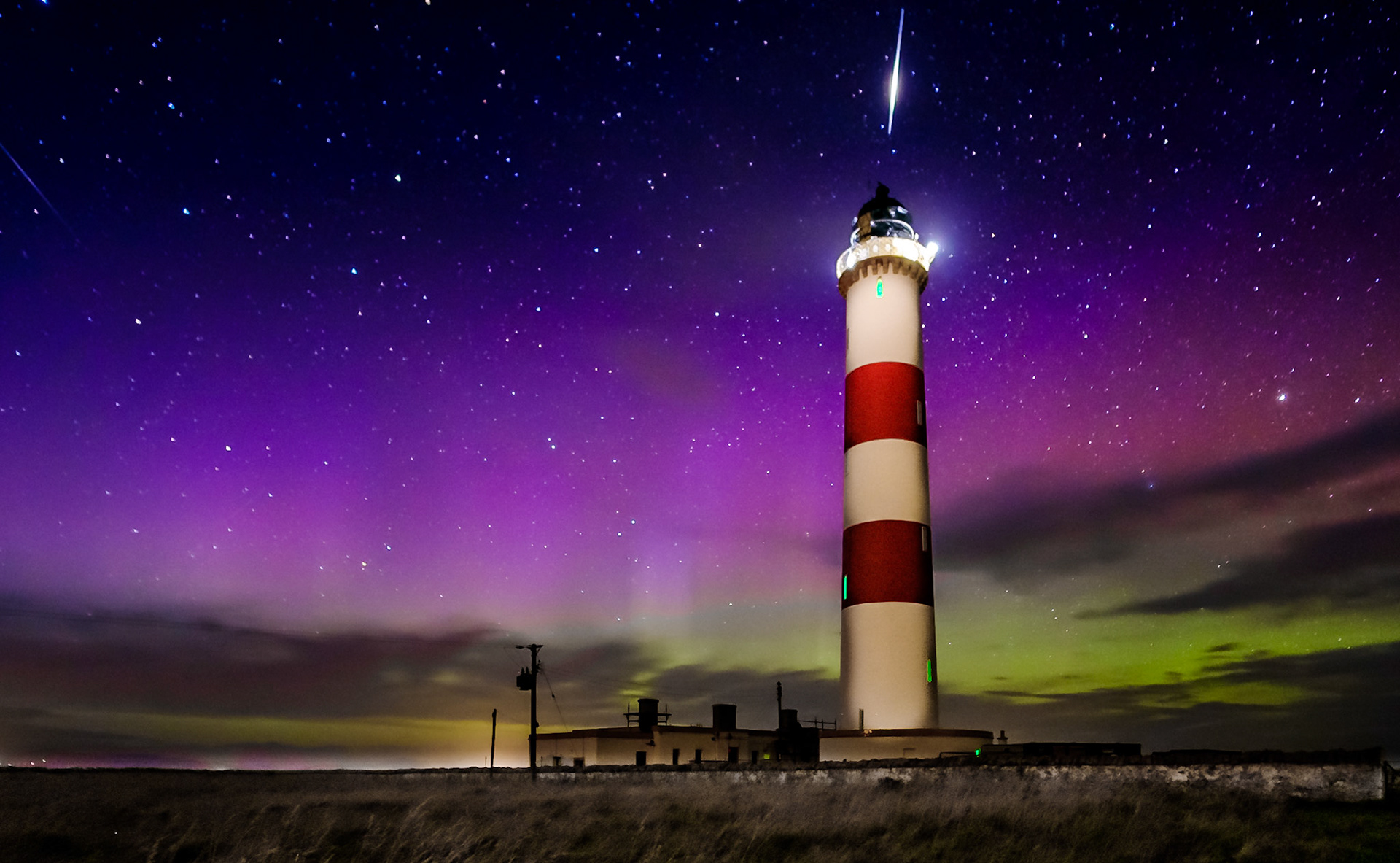 A shooting star heads to Earth during an Aurora display at the iconic Tarbatness lighthouse