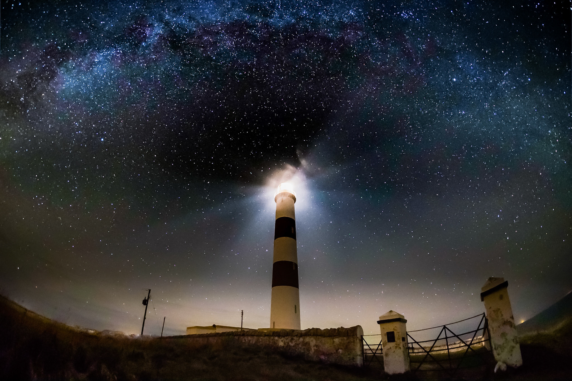 A wide view of the Tarbatness Lighthouse with the milky way above.
