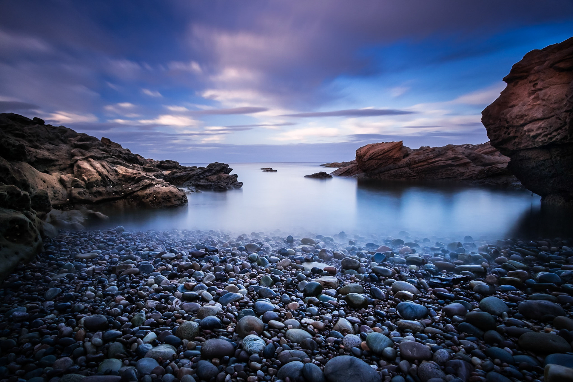 A long exposure captures the last of the daylight over a calm sea.