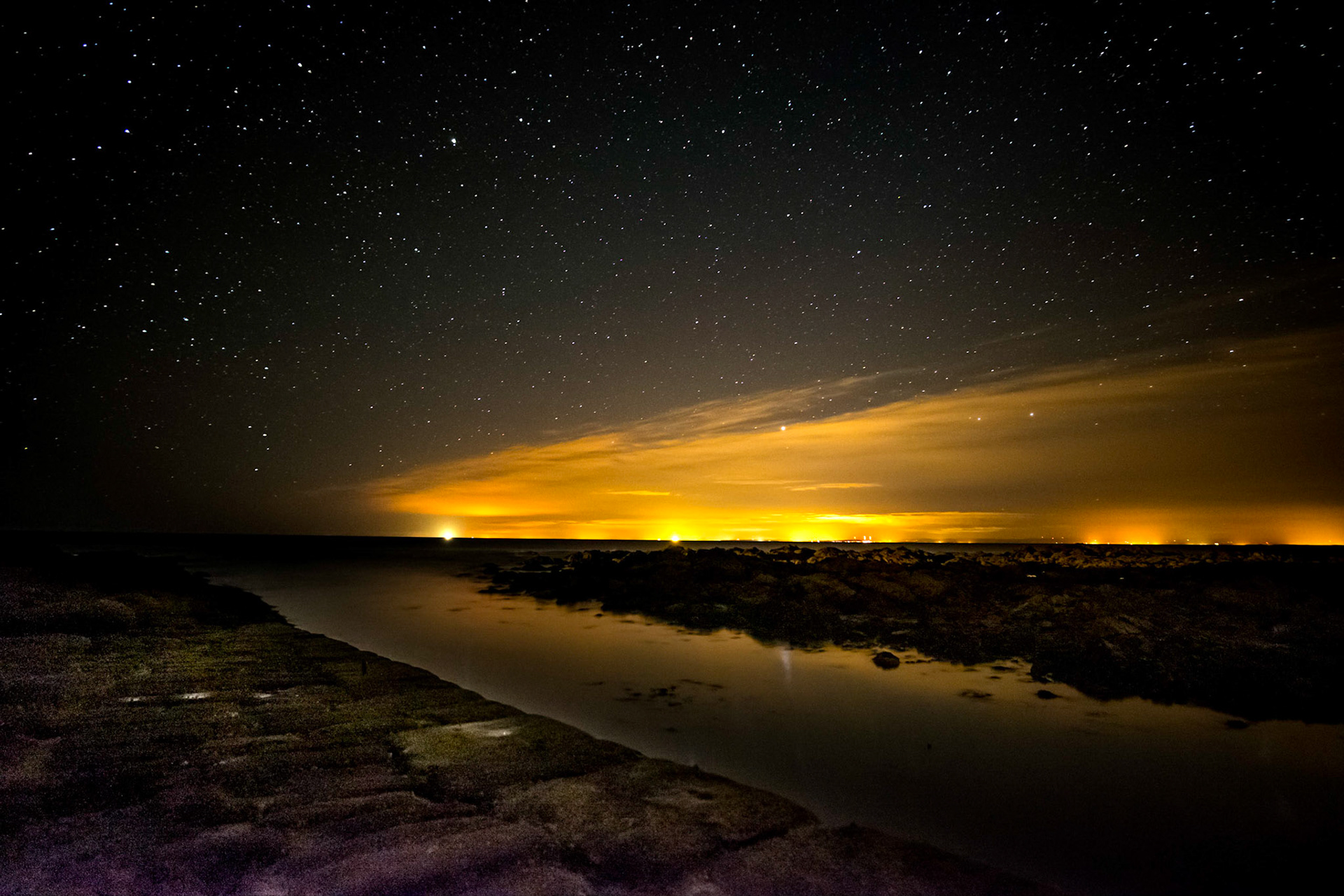 The jetty at Wilkhaven, with the towns of Moray lighting up the night sky.
