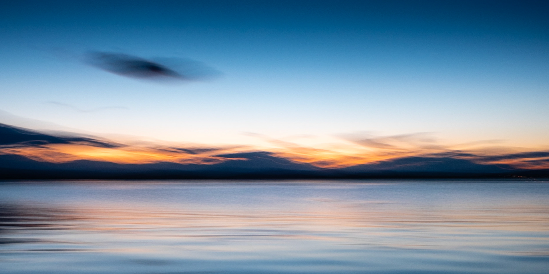 The summer sun dips below the hills across the Dornoch Firth, with the clouds forming a "second layer of hills".