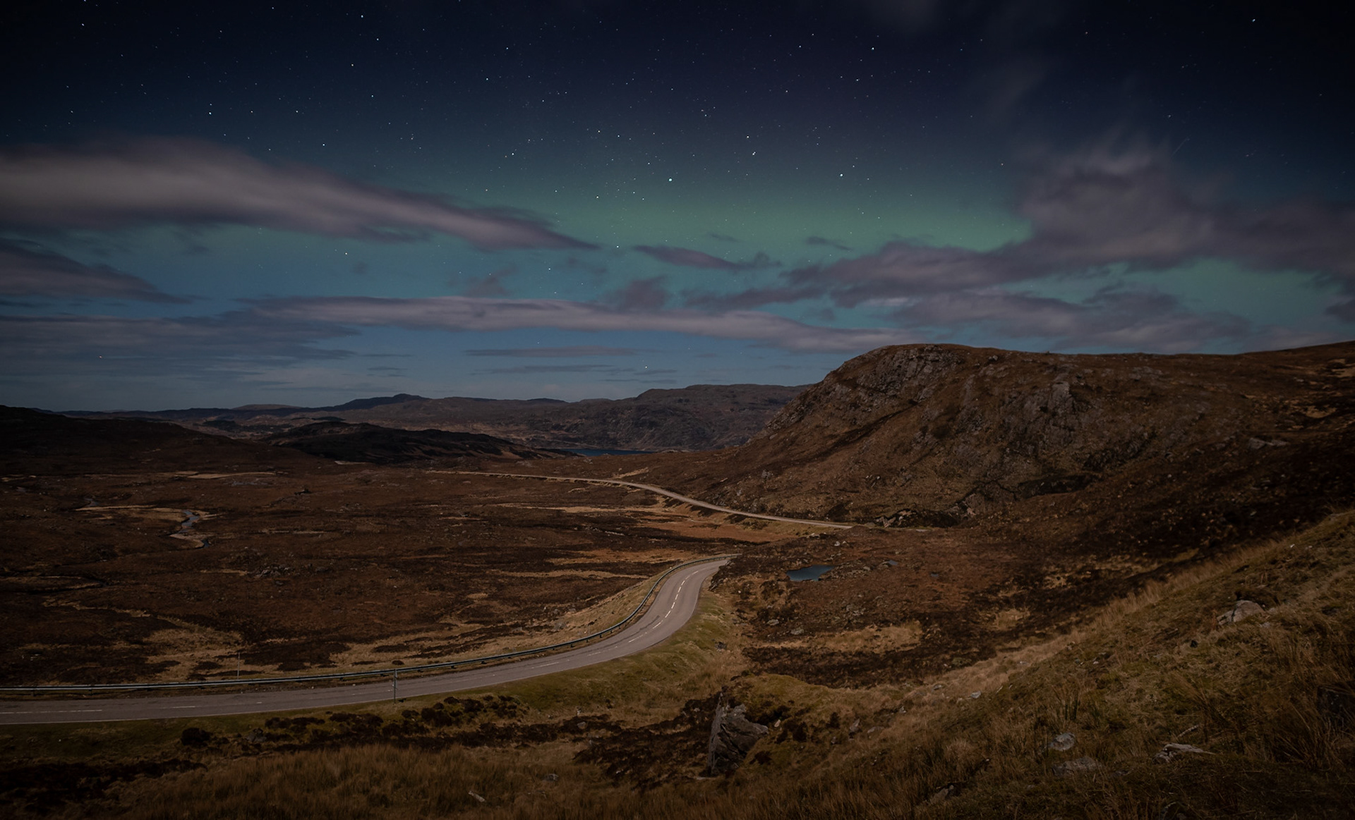 The lonely A894 road snakes into the raw landscapes of Scotland's far northwest, with only the stars and a touch of aurora for company.