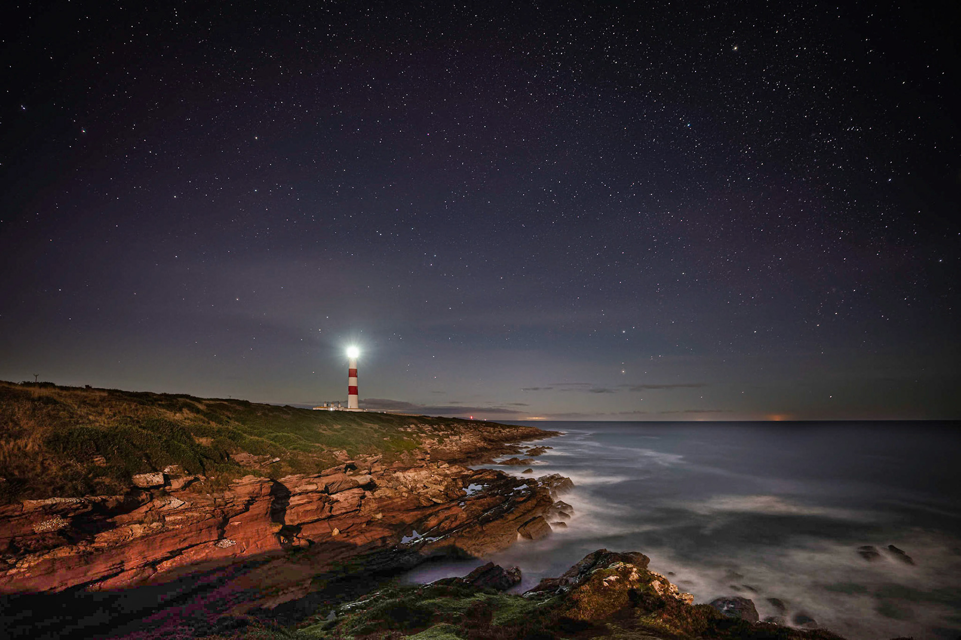 Tarbatness Lighthouse, with the lights of the North Sea oil platforms just visible on the horizon.