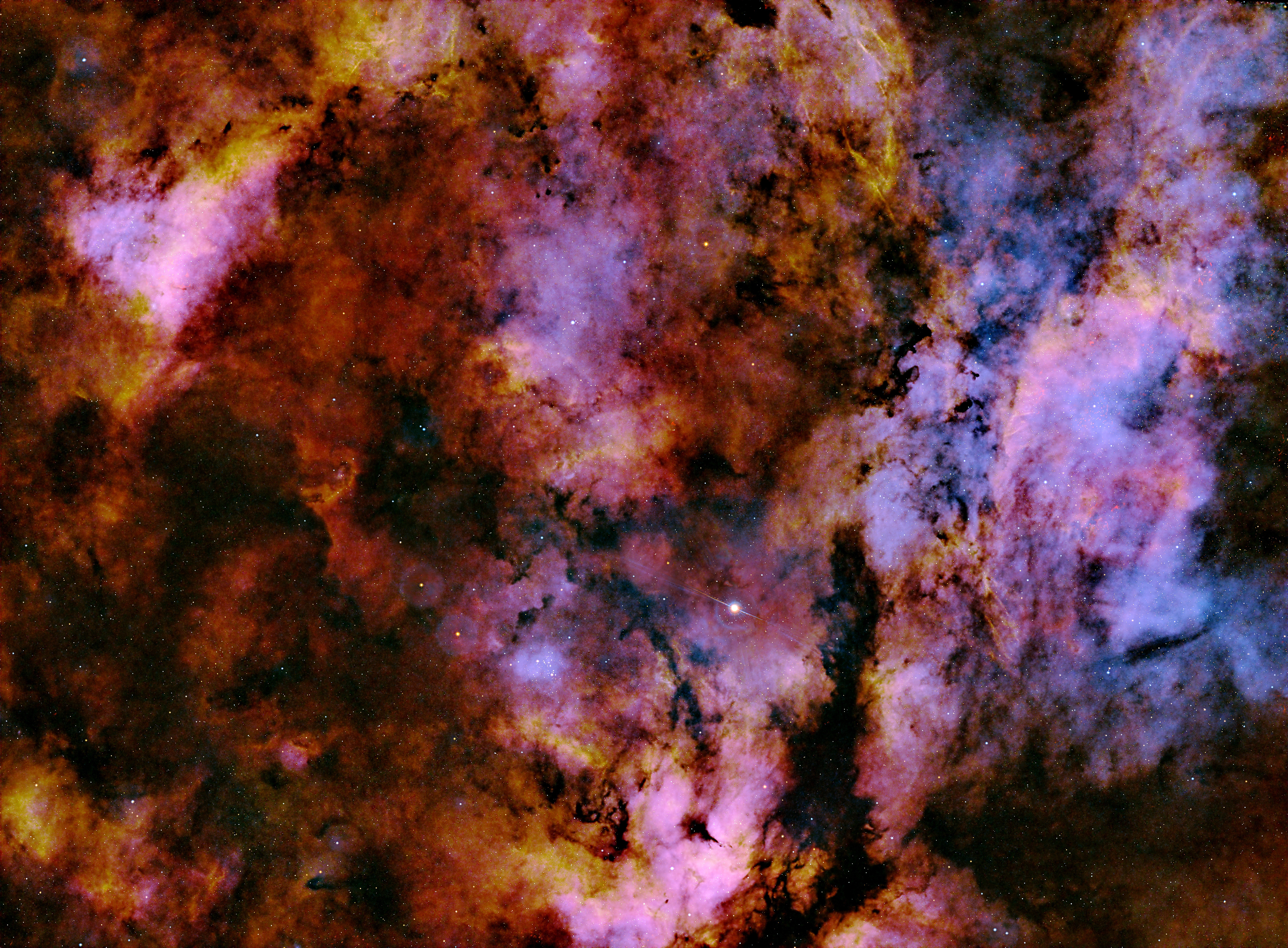 This colorful image is of the Gamma Cygni Nebula, also known as the Sadr Region or IC 1318. It is a diffuse emission nebula that can be seen around Sadr (Gamma Cygni), the star near the center of the image. Despite the name, the star and the nebula are unrelated. Even though it looks embedded in the nebulosity, Sadr is approximately 1,800 light years distant, while the nebula is much further away, at 4,900 light years.  The Gamma Cygni Nebula is considered an emission nebula because it is ionized by the radiation of the nearby stars and it emits visible light as a result. The visible portion of the H II region stretches over an area more than 100 light years across. The nebula is illuminated by an O9-class star which is visually obscured by interstellar material.
