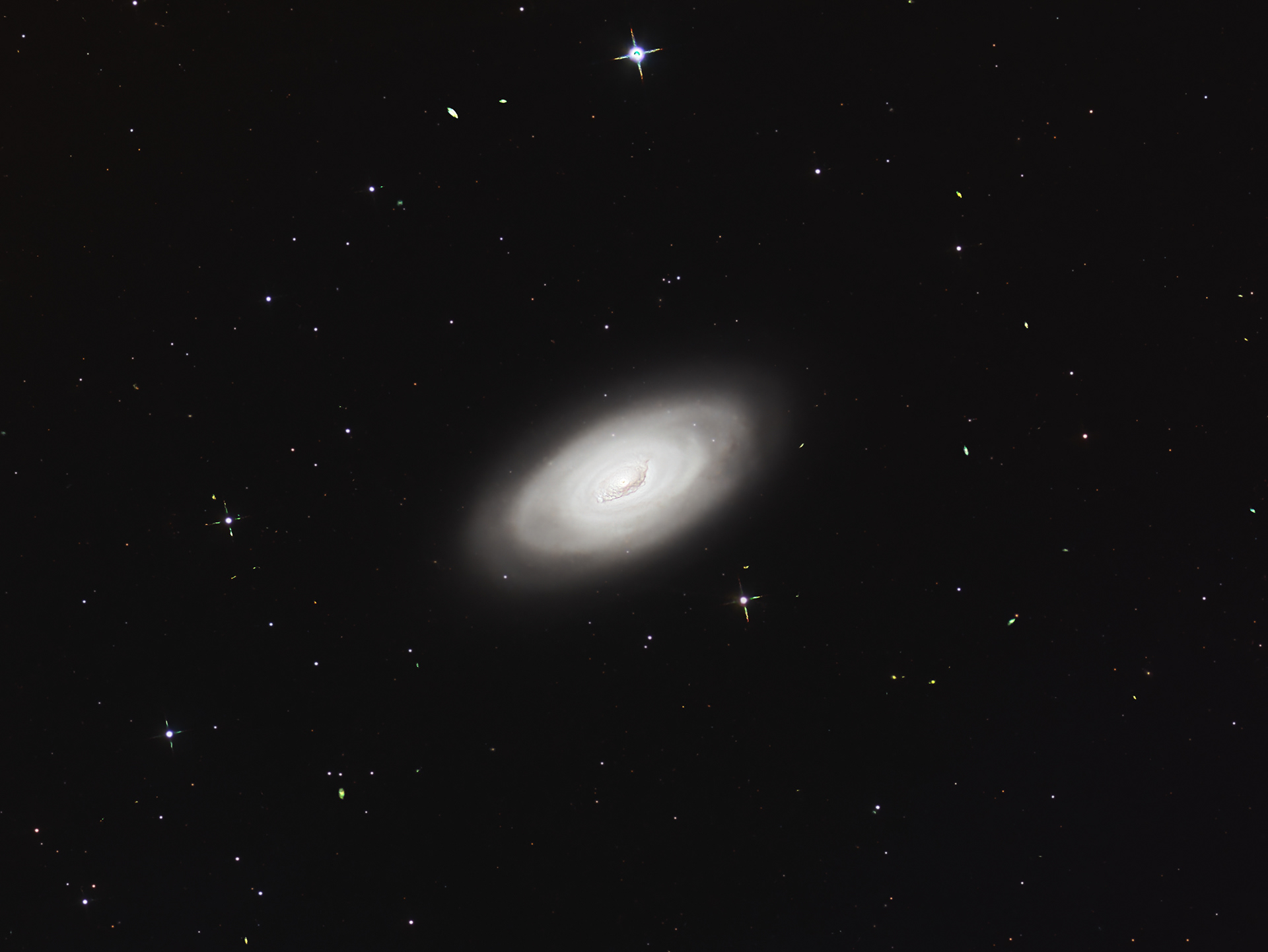 Messier 64 (M64), also known as the Black Eye Galaxy, Evil Eye Galaxy, or Sleeping Beauty Galaxy, is a famous spiral galaxy located in the constellation Coma Berenices. It gets its name because with certain processing the center bulge has darker matter on the earth facing side, like a black eye. I chose to process it to show the full extent of the galaxy. Actually, galaxies, as what we see is the result of a collision of two galaxies about a billion years ago. This resulted in the inner bands rotating in the opposite direction as the outer bands!  Messier 64 has an apparent magnitude of 9.36 and lies at a distance of 24 million light years from Earth. It contains and estimated 100 billion stars!