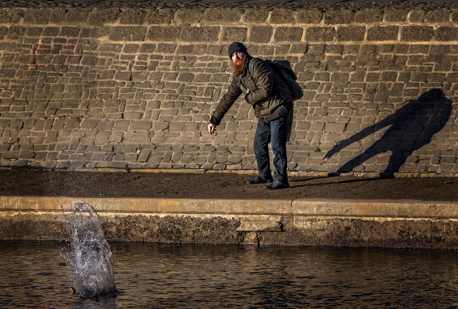 Colourful local character in York throwing stones in the river Ouse.
