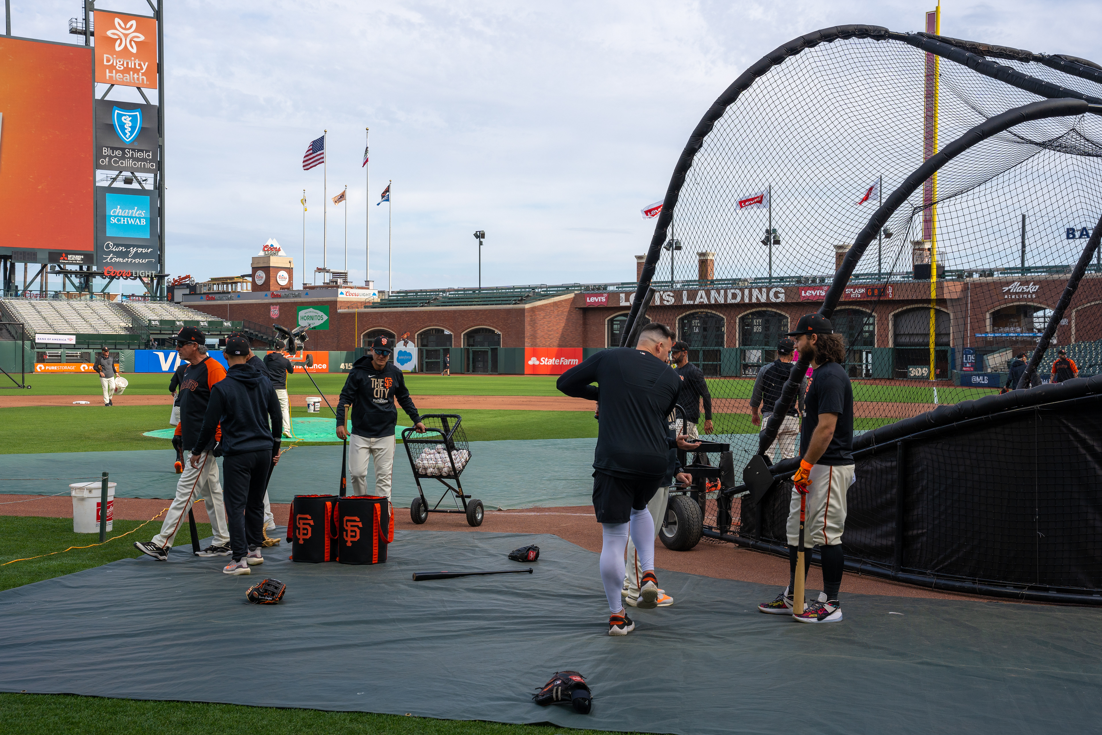 A hitting coach demonstrates a swing to Brandon Crawford, standing to the right.