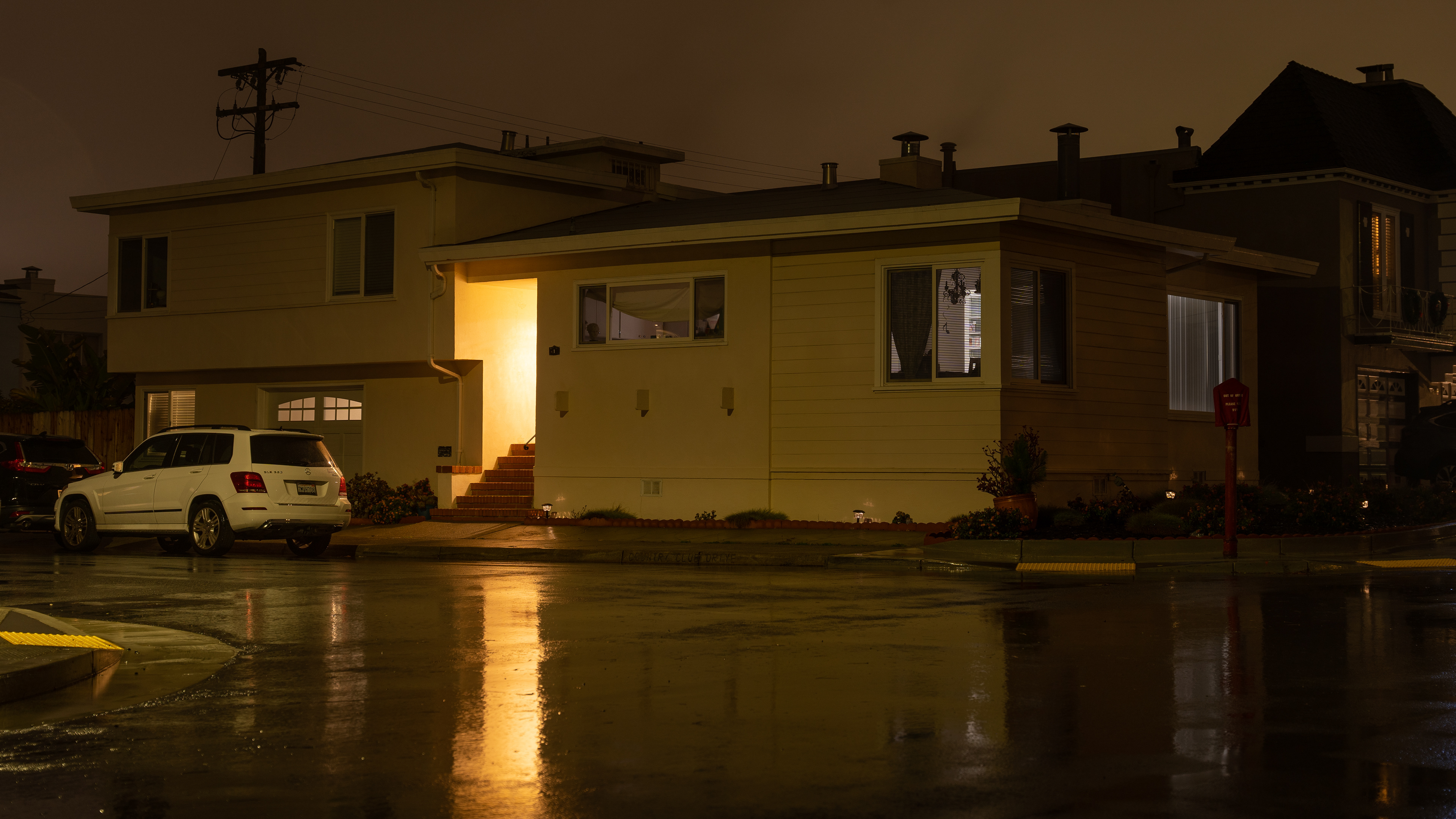 The porch light outside a home reflects in the wet street