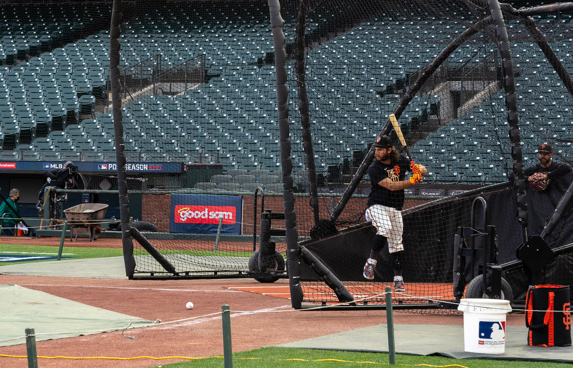 Brandon Crawford loads up on a ball during batting practice. Behind, San Francisco Giants manager Gabe Kapler watches.