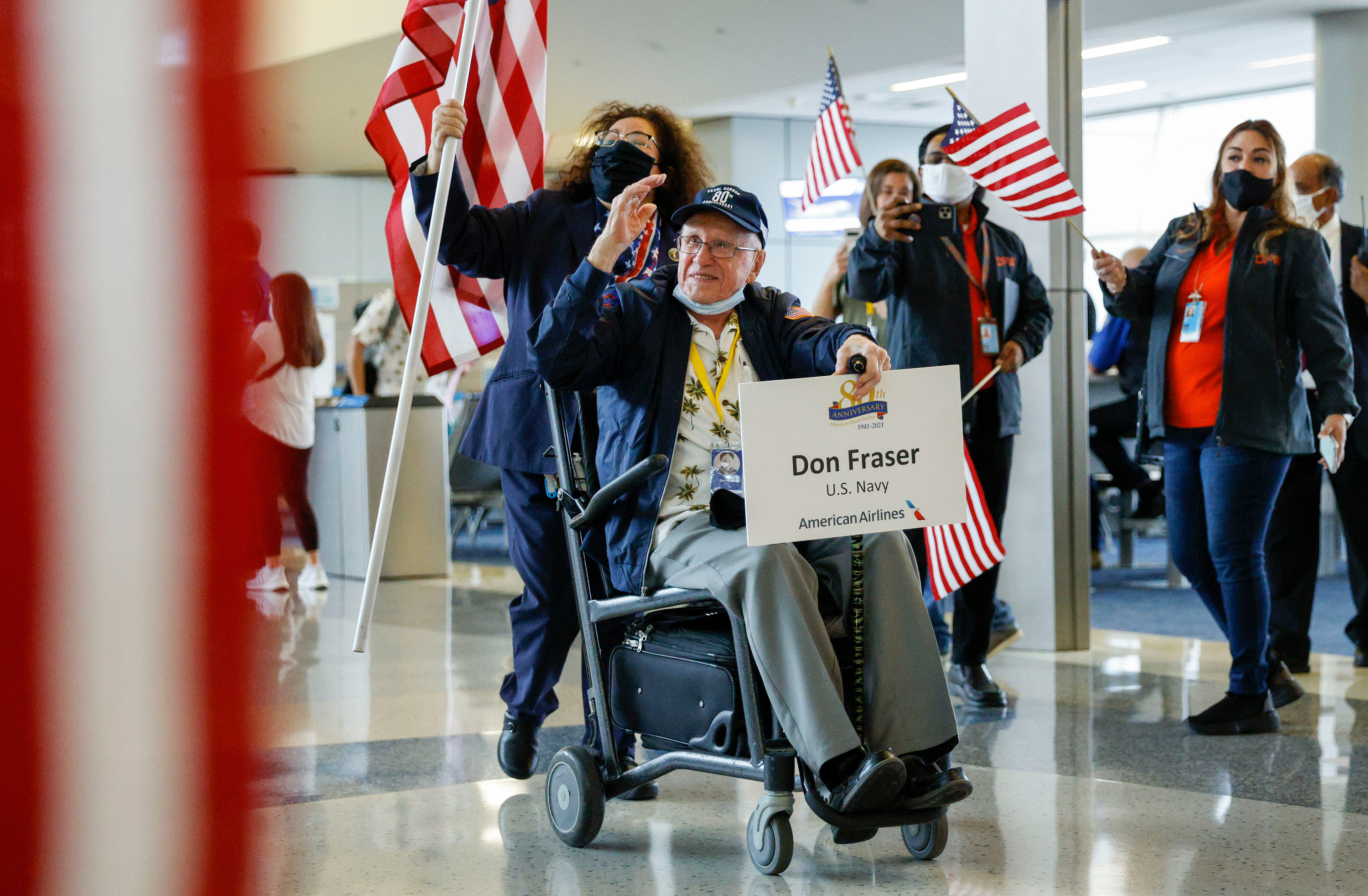 World War II veteran Don Fraser salutes the crowd during a sendoff to Hawaii at Terminal D of Dallas Fort Worth International Airport on Friday, Dec. 3, 2021, in Dallas.