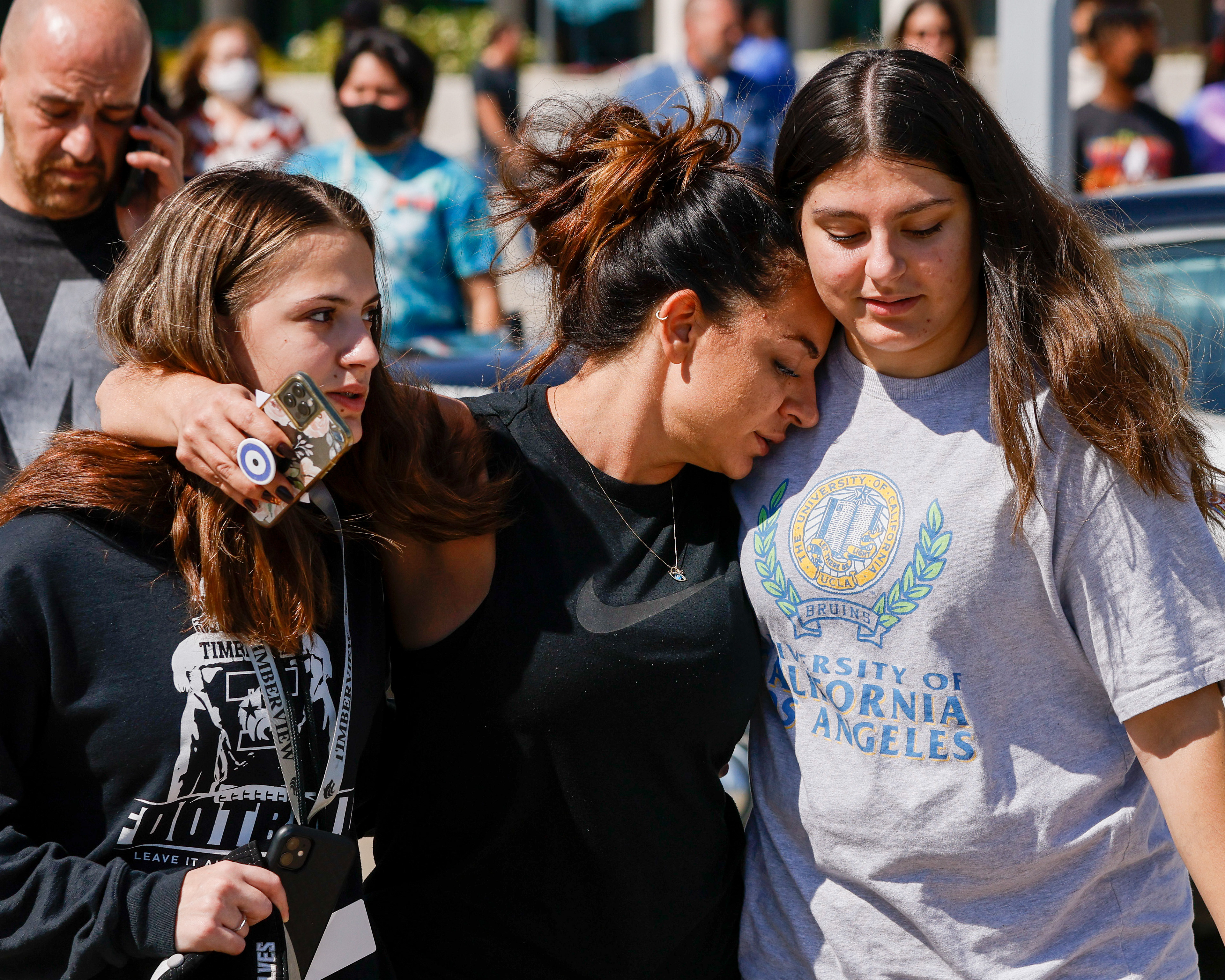 Liz Hasani (center) hugs her daughters Alivia Hasani, 14 (left) and Aminah Hasani, 15, outside of the Mansfield ISD Center for the Performing Arts on Wednesday, Oct. 6, 2021 in Mansfield, Texas. Four people were injured in a shooting at Timberview High School in Arlington on Wednesday morning.