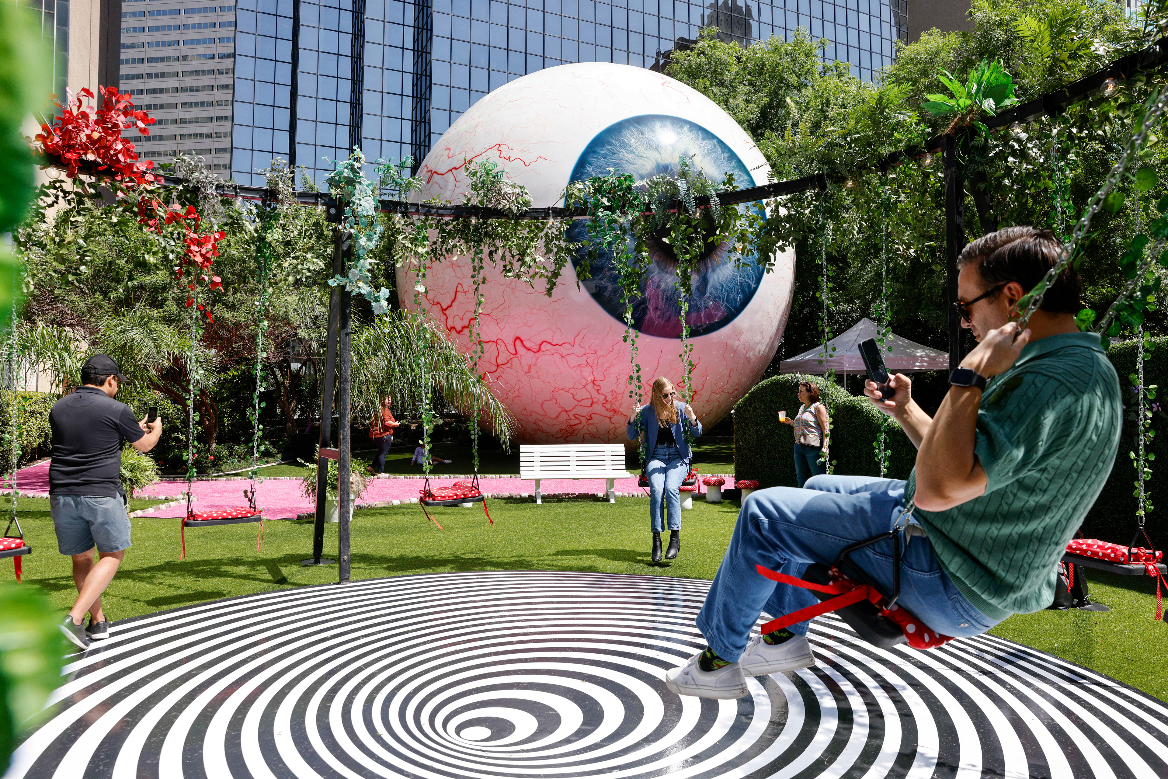 People swing and take photos at the Eyeboretum at The Eye at the Joule on Friday, April 21, 2023 in Dallas. The pop-up space runs April 21-23.