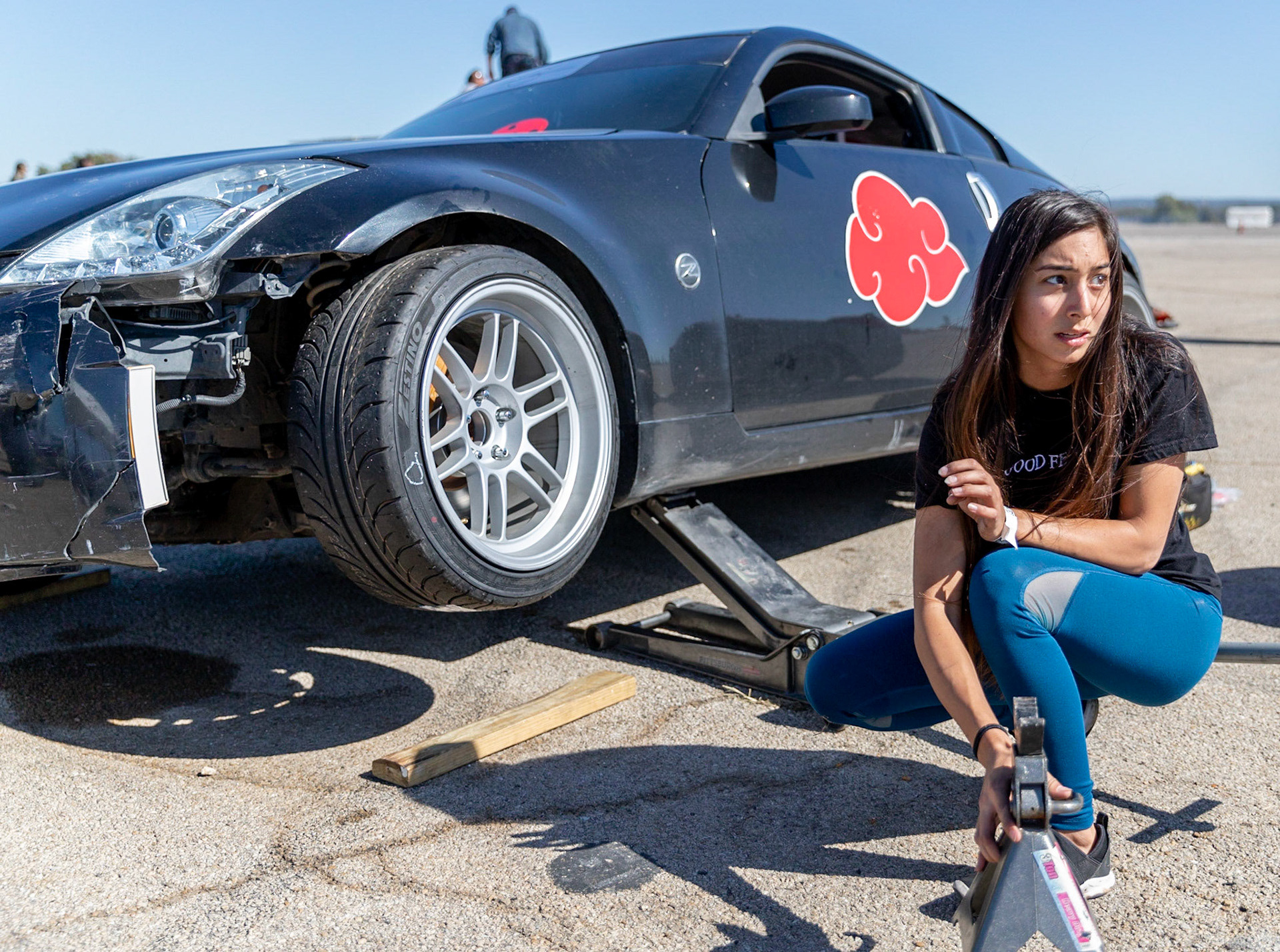 Business management senior Vanessa Stiles places a jack stand under car during the Lone Star Bash drift event Oct. 27, 2019, in Mineral Wells.