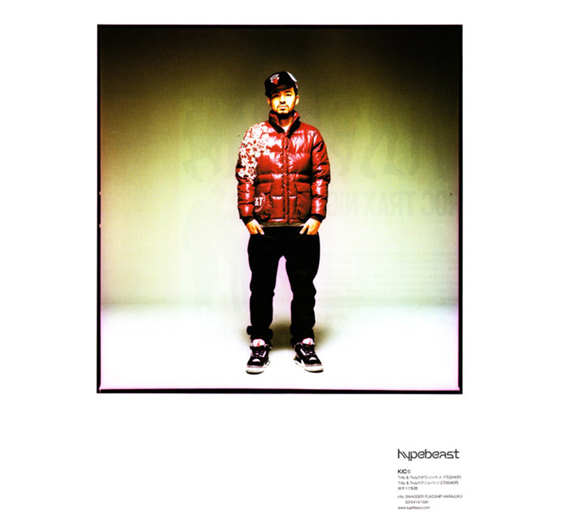 a man wearing a ski puffy jacket, hat, pants and sneakers facing towards the viewer.