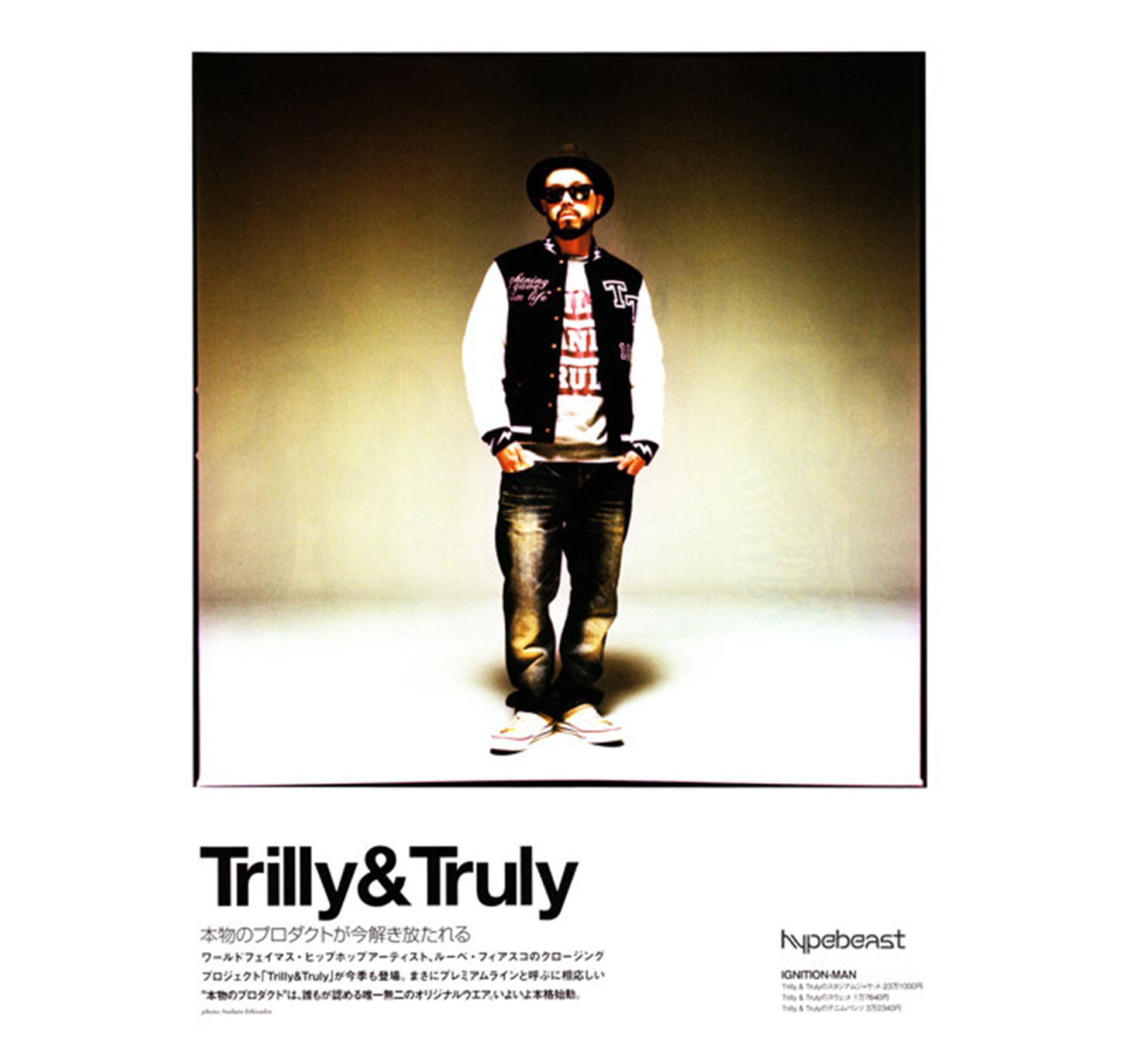 A man wear a jacket, hat and sunglasses, jeans and sneakers looking slight off center.