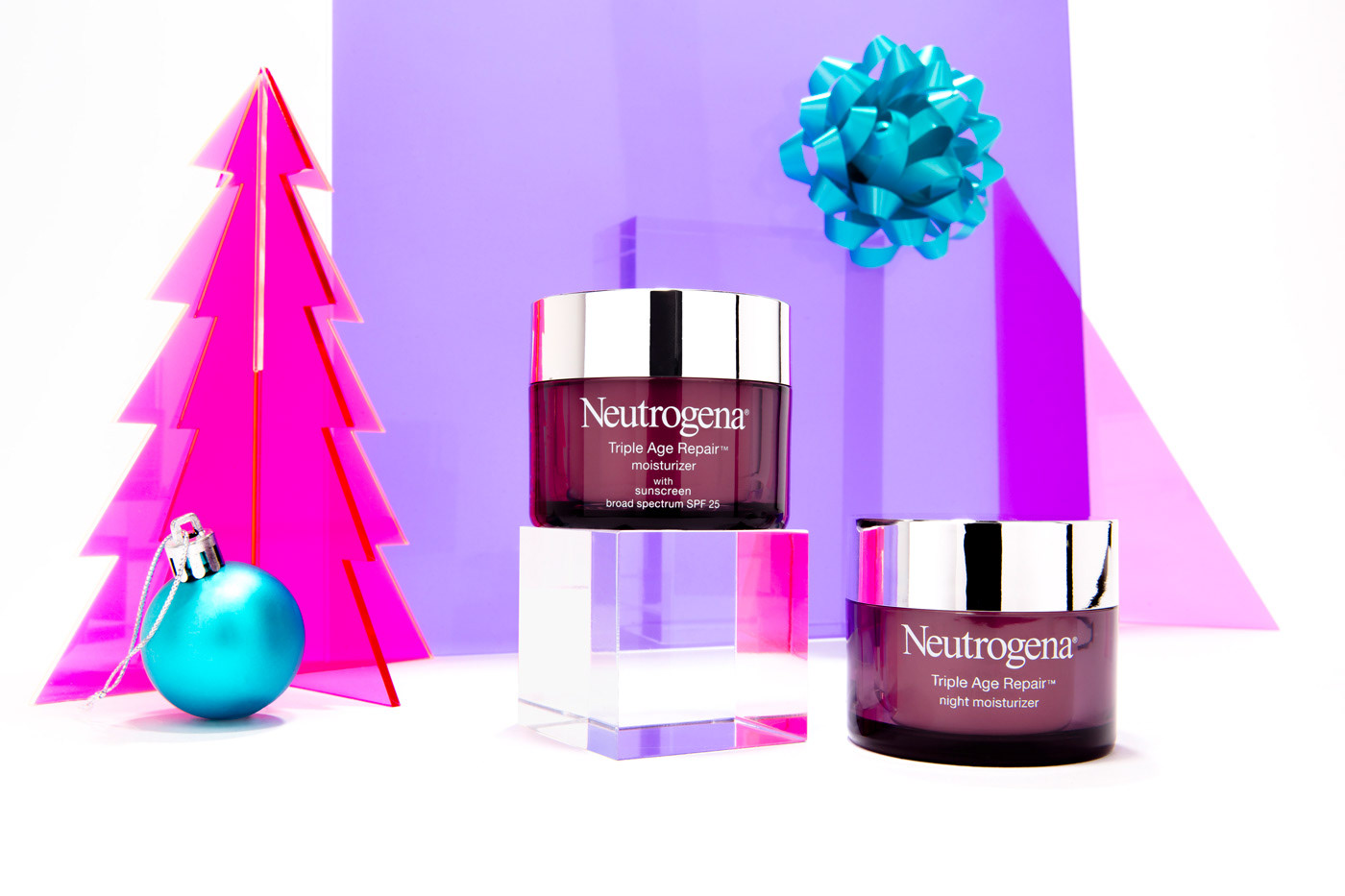 Two skincare moisturizers are styled with neon Christmas trees and other decorations.