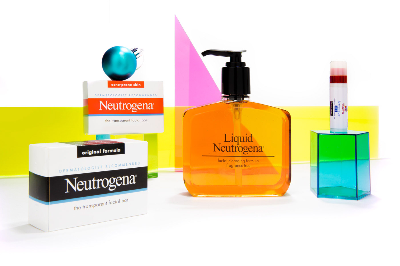 Five skincare products are styled with neon Christmas decorations.