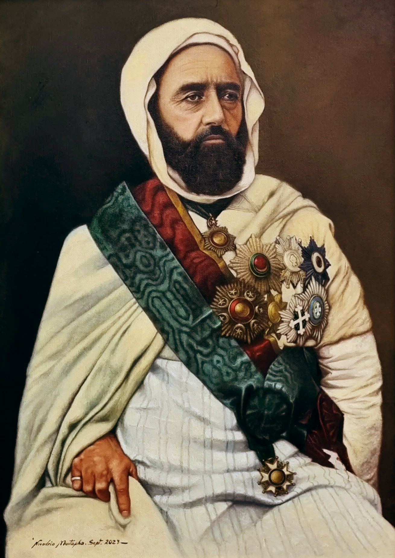 A portrait painting of Emir Abdelkader wearing a white hood, a dark beard, and multiple ornate medals and sashes across his chest. He is seated, with his left hand resting on his lap. The painting includes a signature at the bottom left corner.