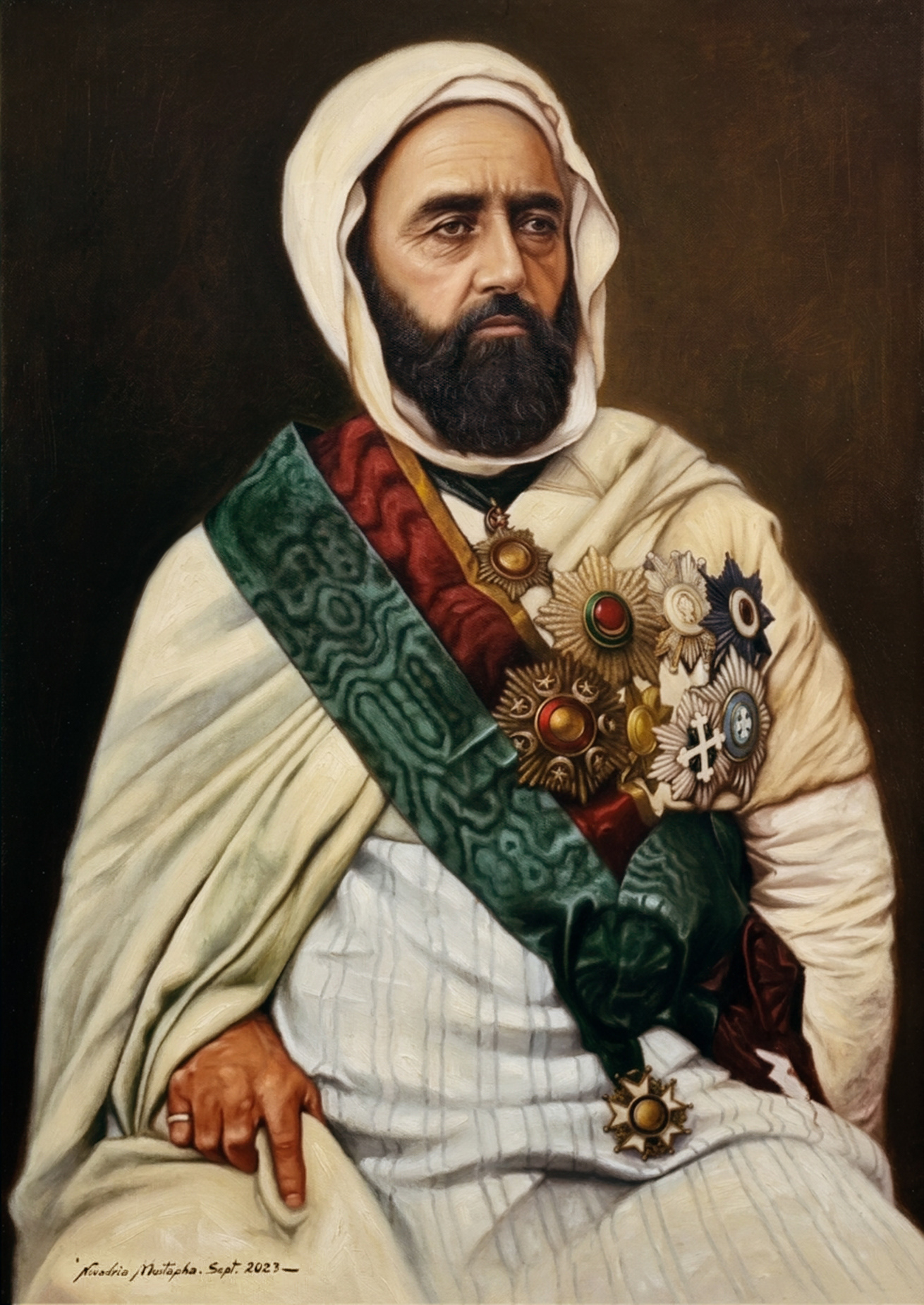 A portrait painting of Emir Abdelkader wearing a white hood, a dark beard, and multiple ornate medals and sashes across his chest. He is seated, with his left hand resting on his lap. The painting includes a signature at the bottom left corner.