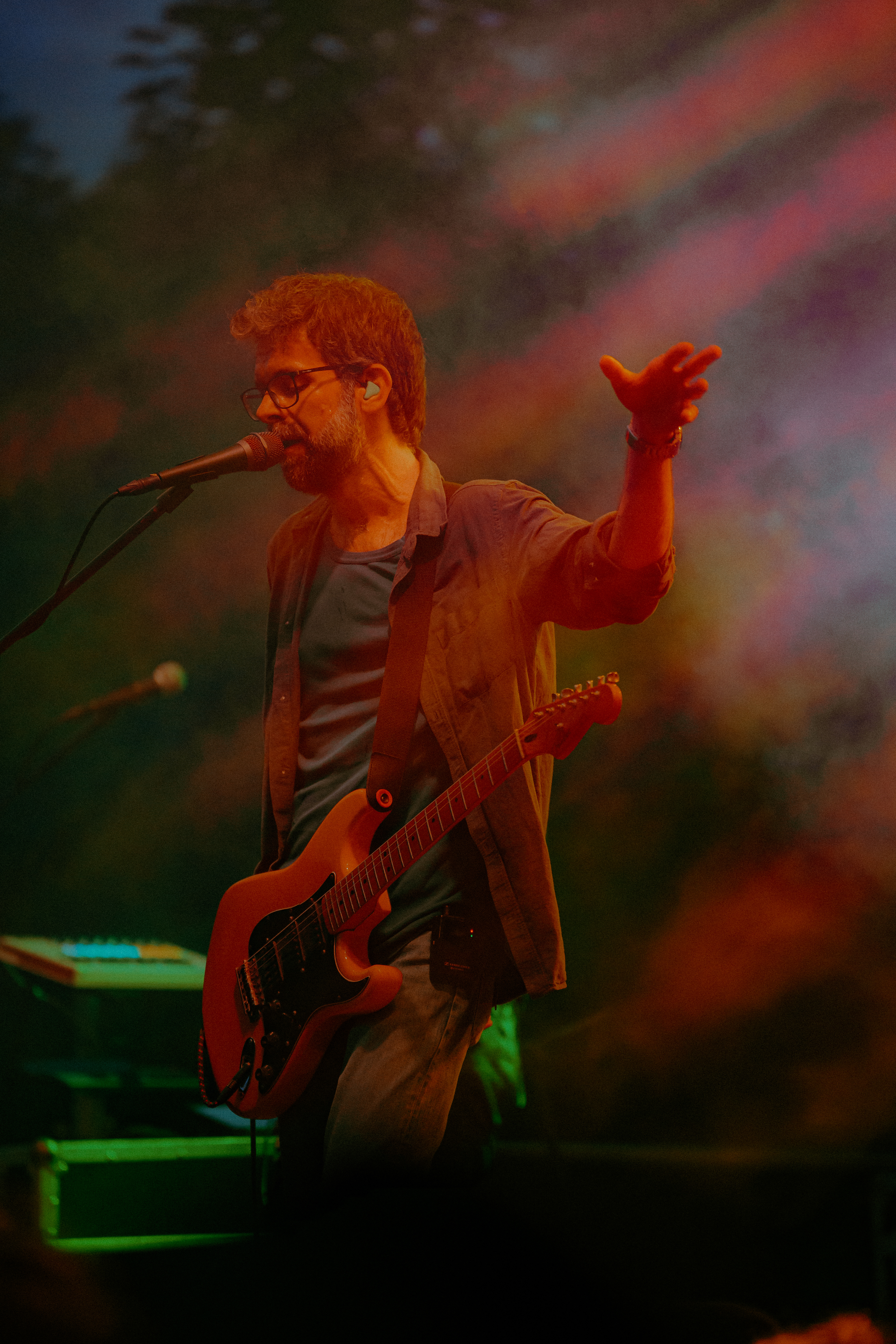Concert photography of Robin and the Backstabbers vocalist singing with intense emotion under dramatic red stage lighting.