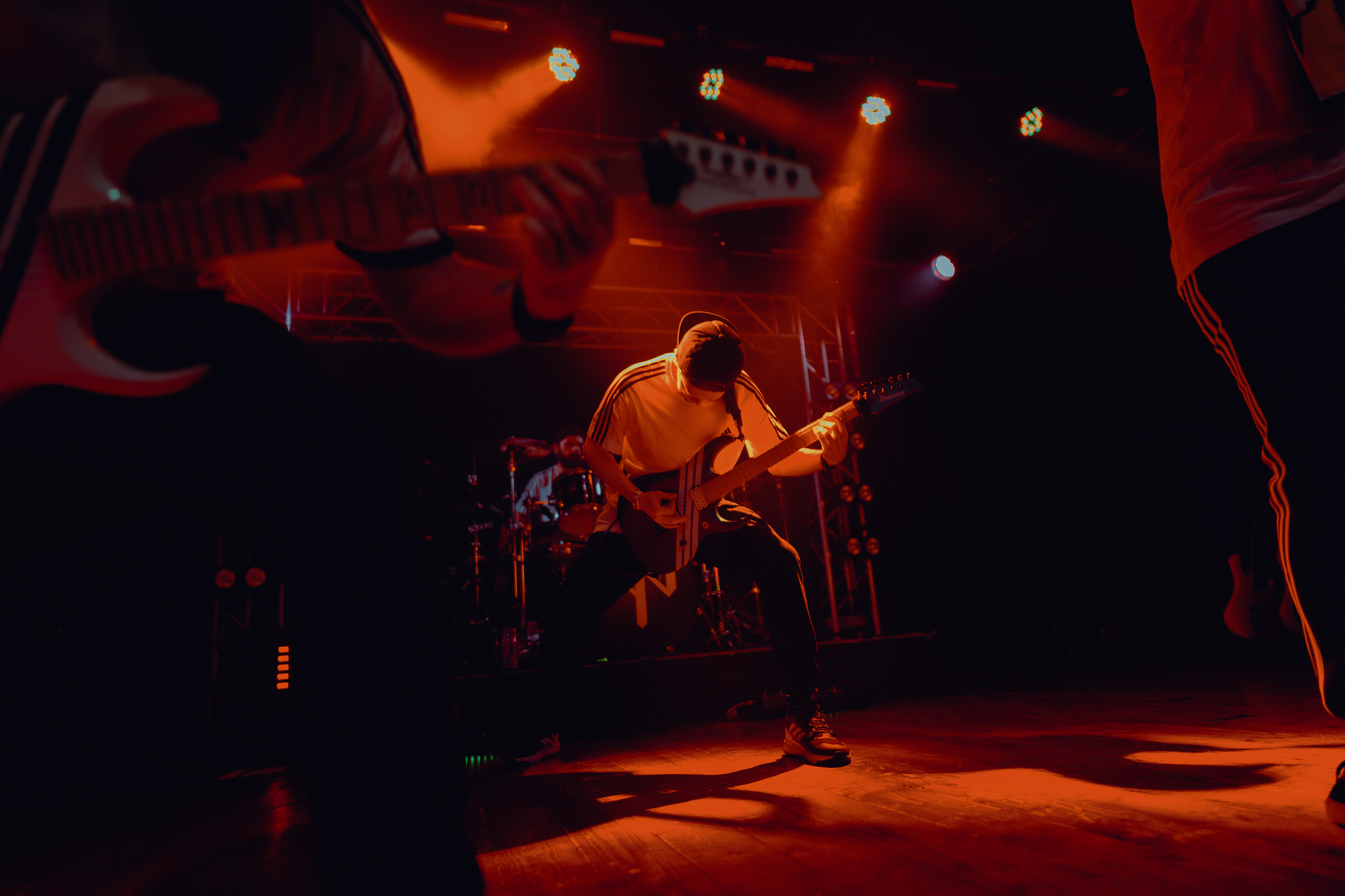 Concert photography featuring guitar close-up in the foreground, with the guitarist singing and playing in the background during the live show at Rockstadt Club in Brașov, Romania.