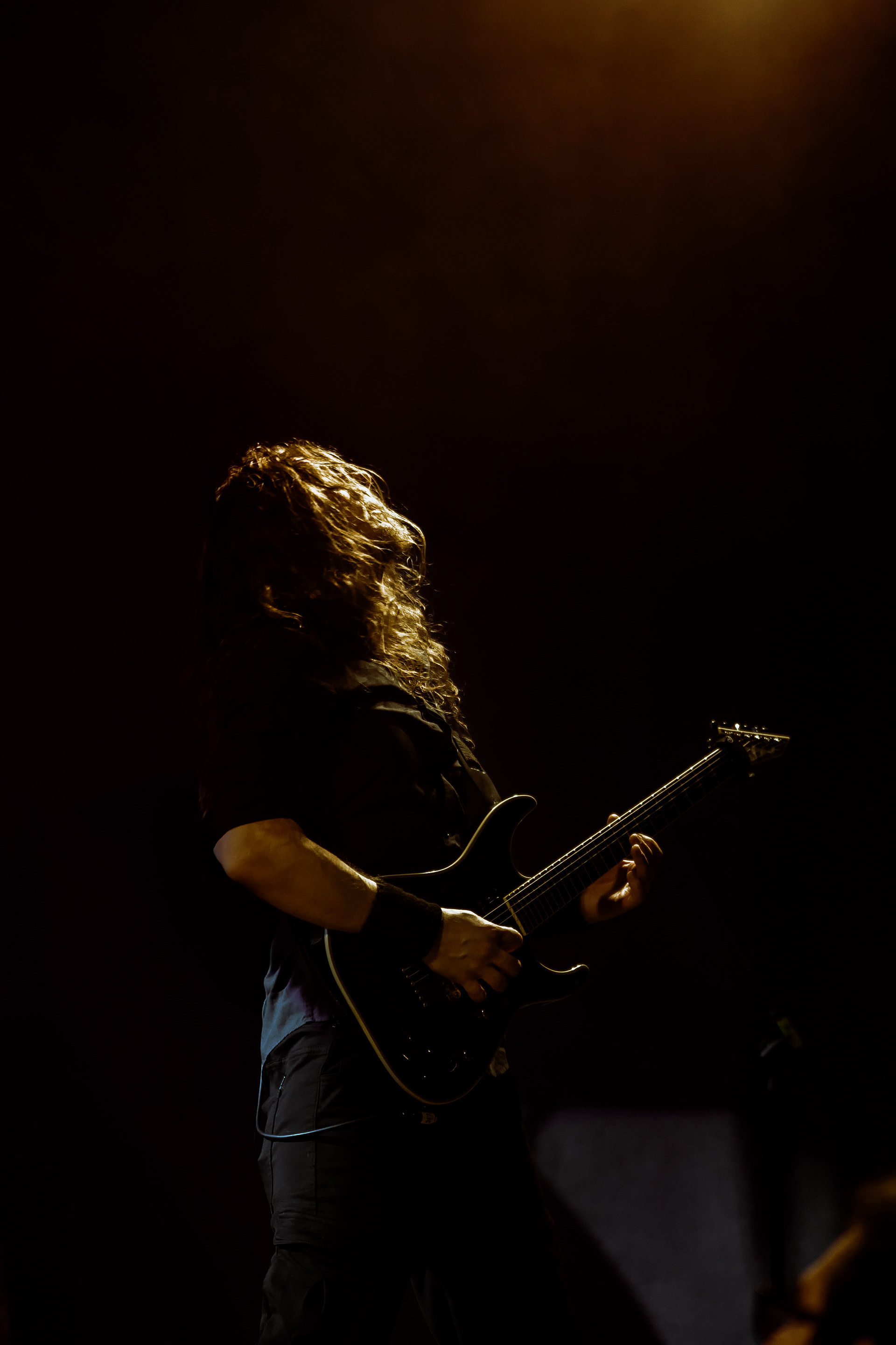 Concert photography close-up of Machiavellian God’s guitarist face lit and looking upward while performing at Rockstadt Club in Brașov, Romania.