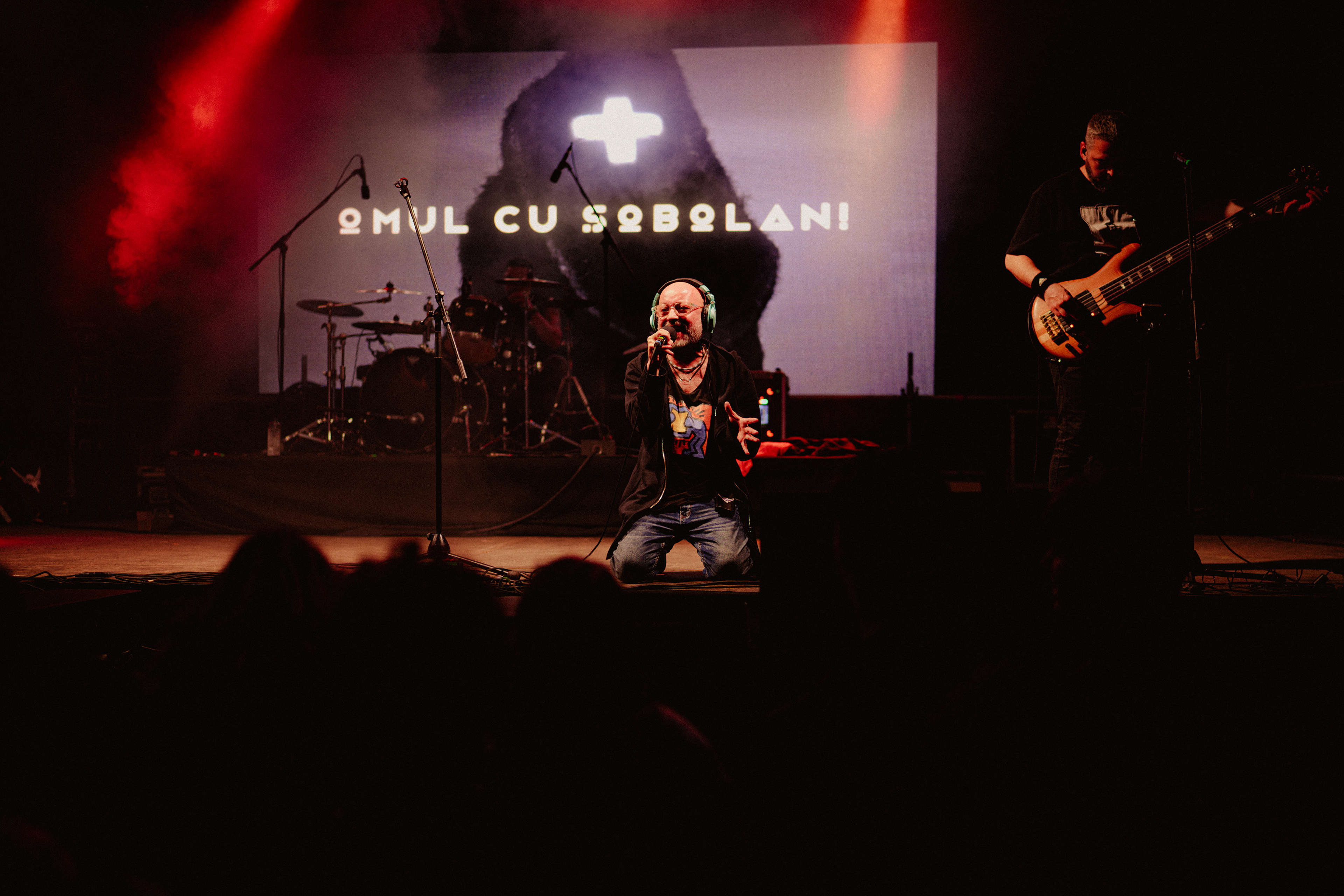 Live performance photography showing Omul cu Șobolani’s vocalist on his knees, deeply immersed in the music and singing passionately.