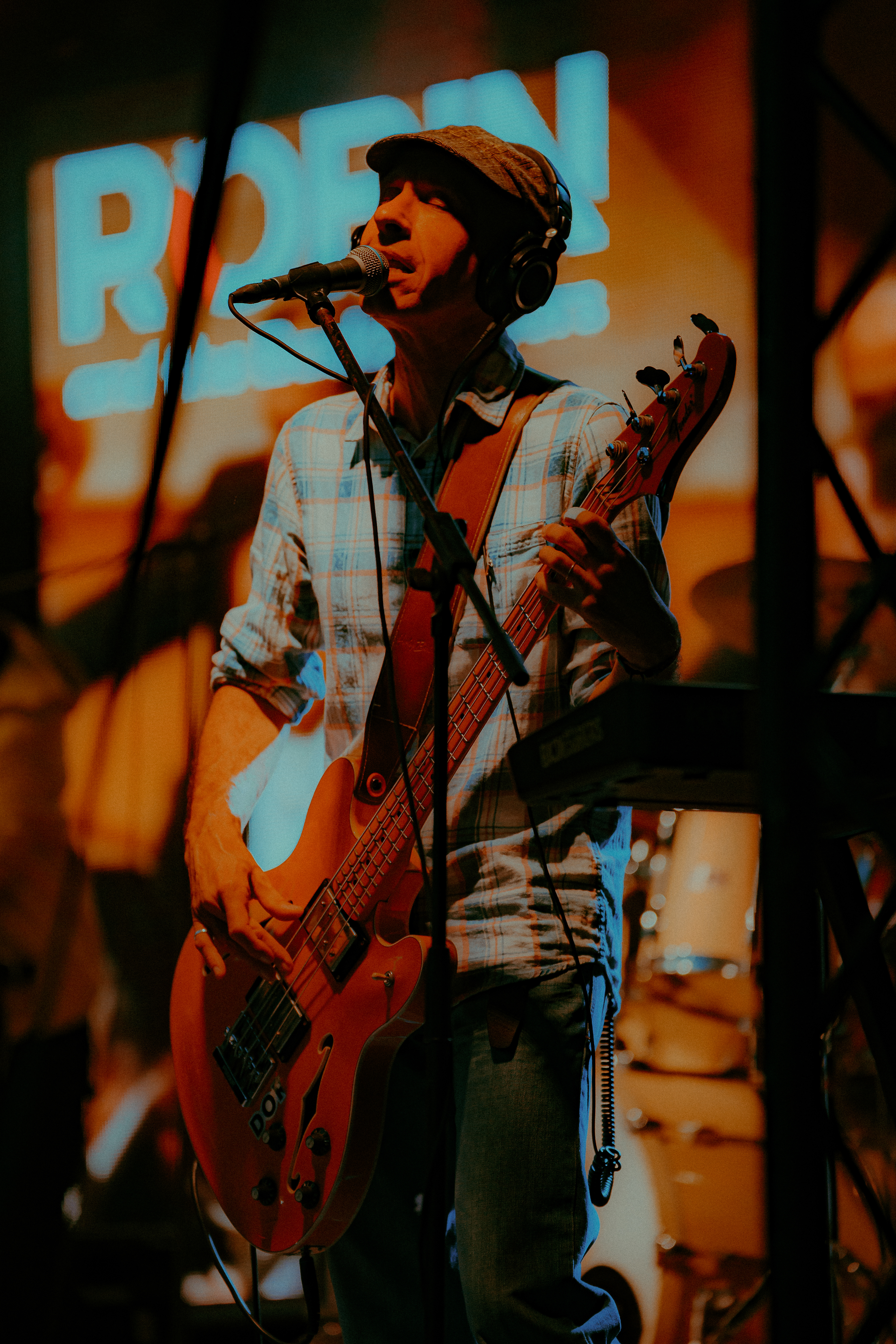 Live event photography of Robin and the Backstabbers bassist singing melancholically while playing bass and providing vocals.