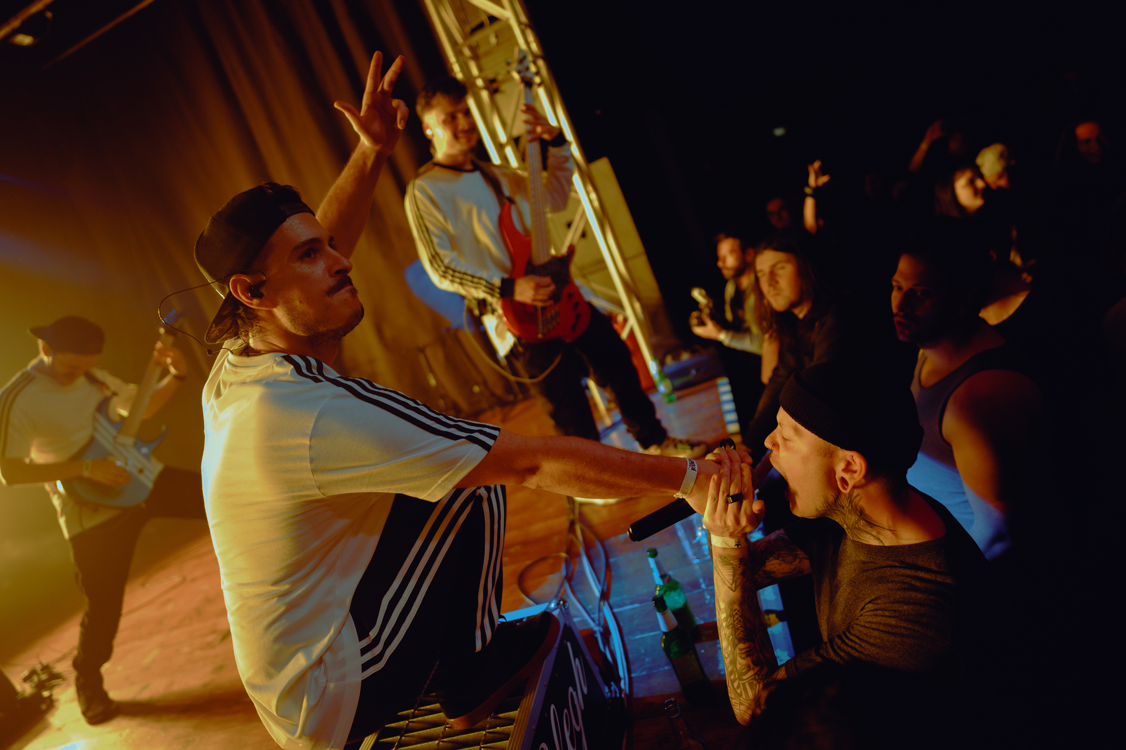Concert photography capturing the vocalist handing the microphone to a fan in the crowd, who is singing along during the show at Rockstadt Club in Brașov, Romania.