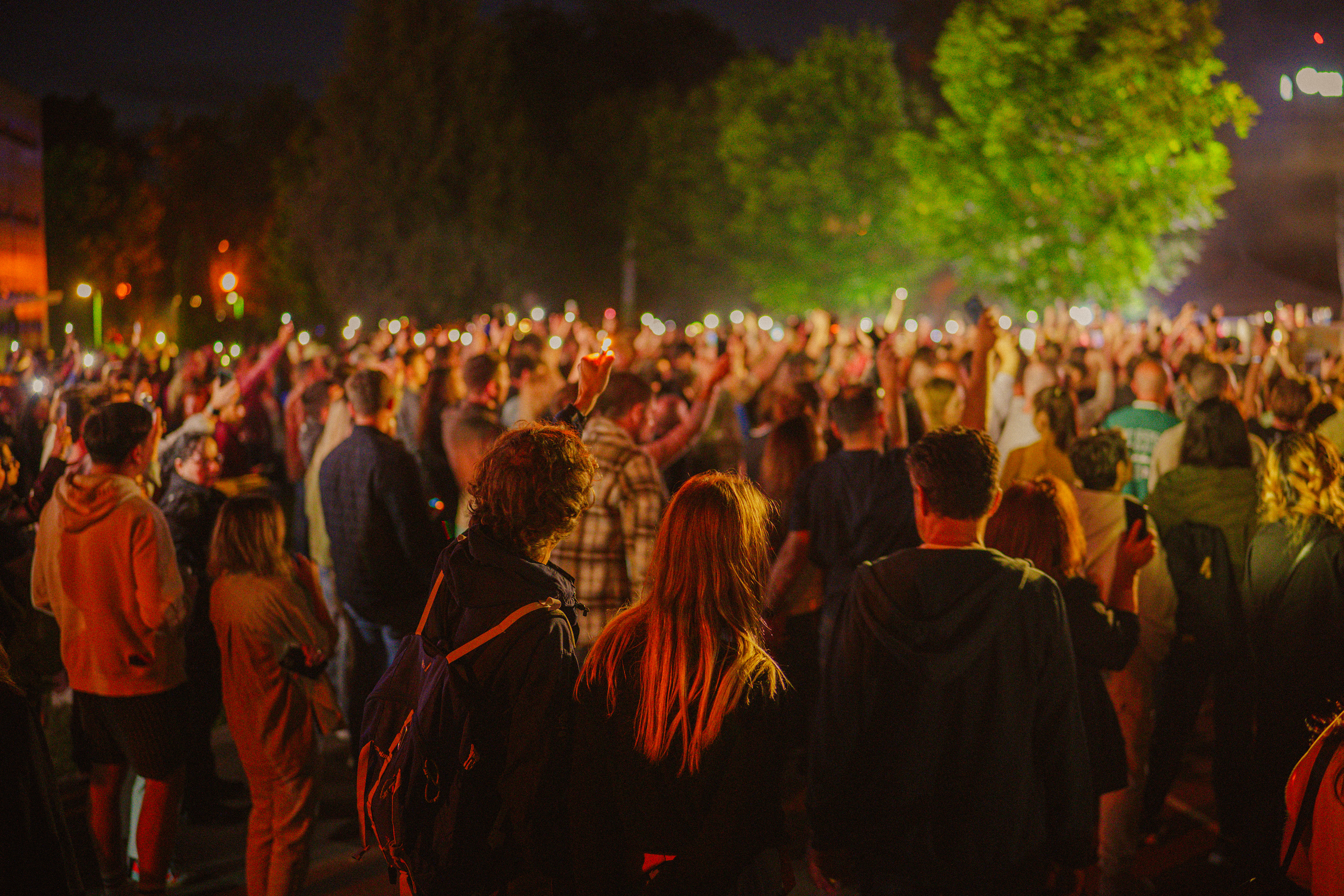 Concert photography showing the crowd holding flashlights while a focused couple holds a lighter during Om La Luna’s show.
