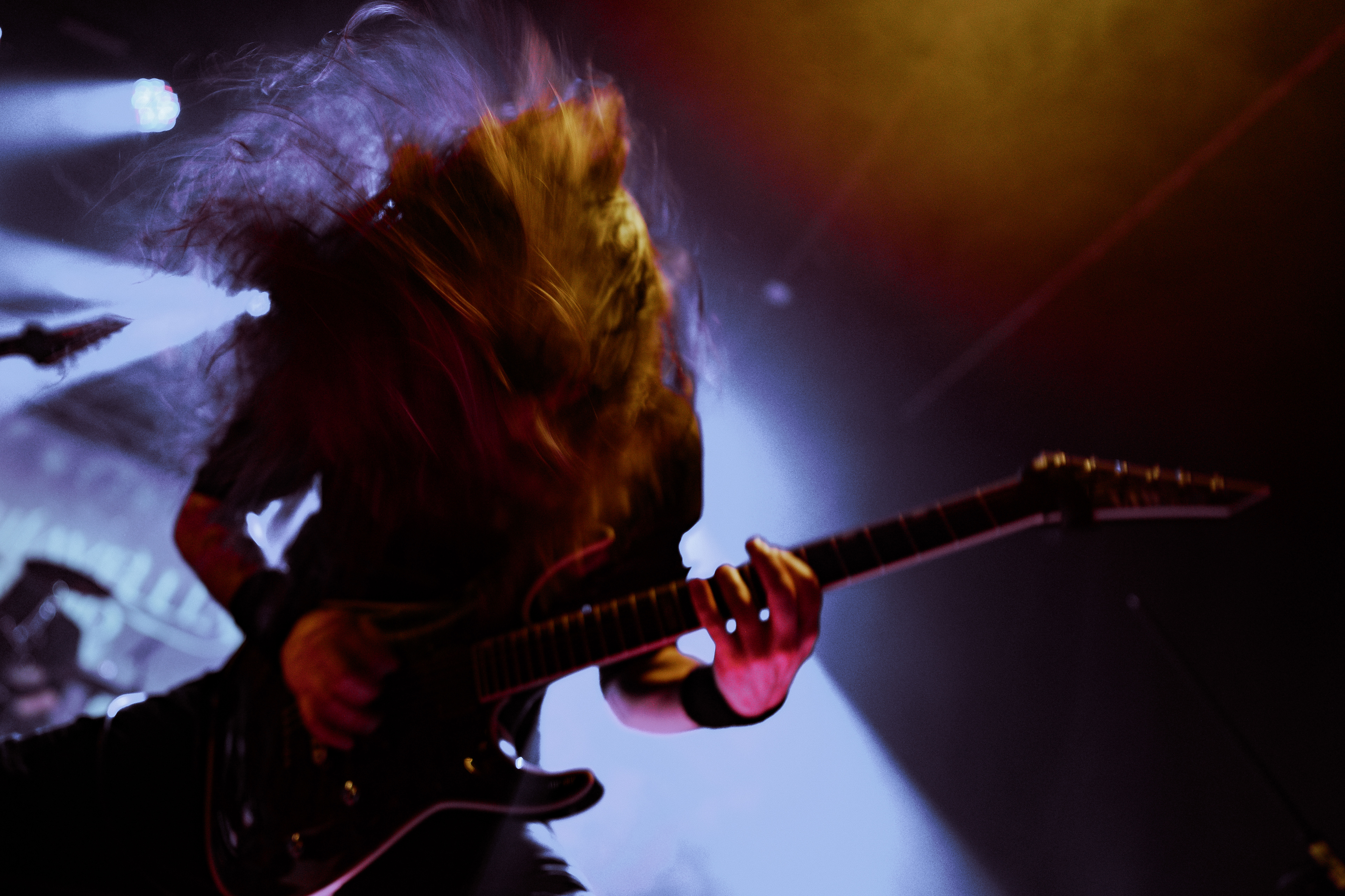 Motion blur concert photography capturing Machiavellian God’s guitarist headbanging energetically during a live show at Rockstadt Club, Brașov.