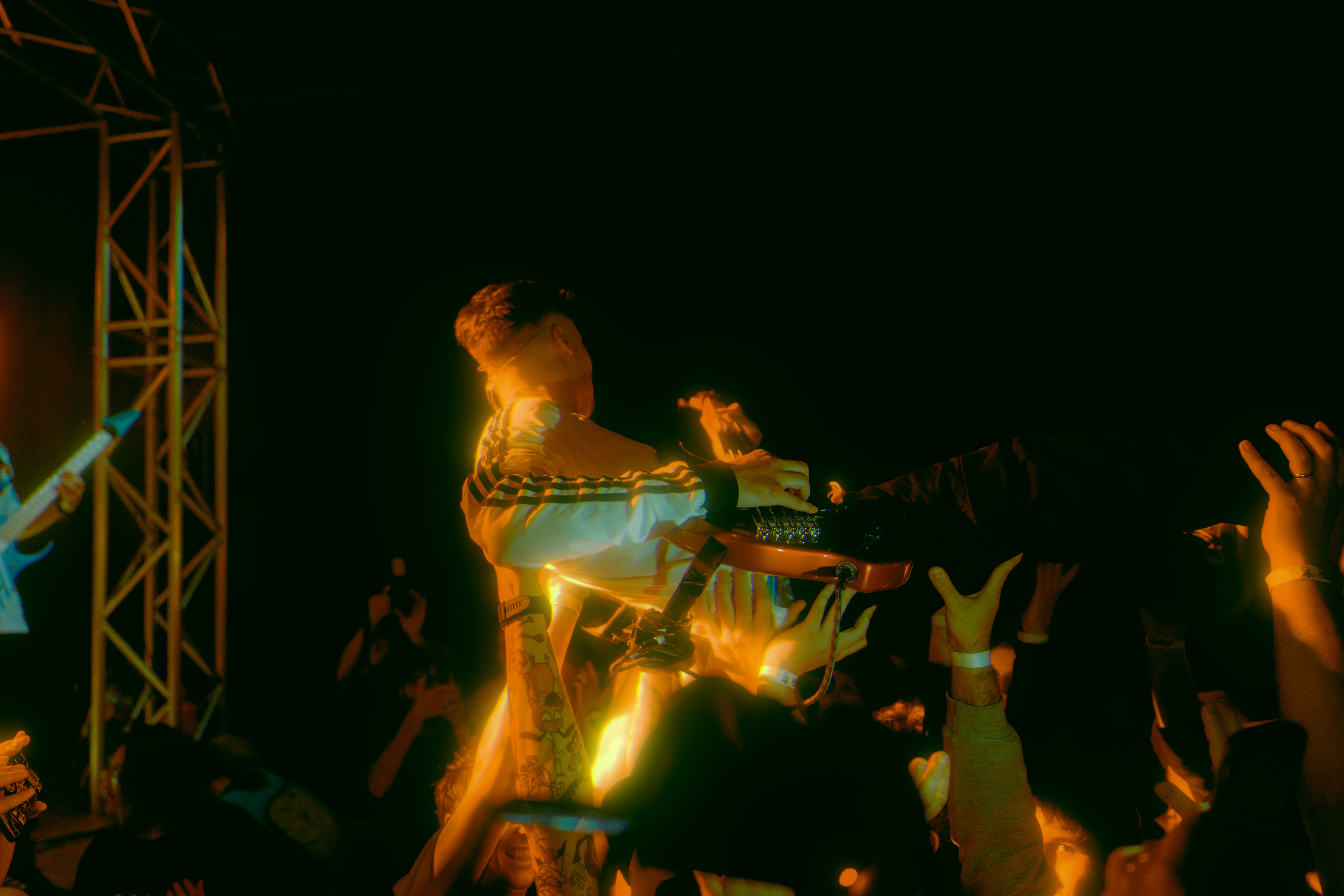Concert photography capturing the bassist of W3 4R3 NUM83R5 singing energetically while crowd surfing during the live show at Rockstadt Club in Brașov, Romania.