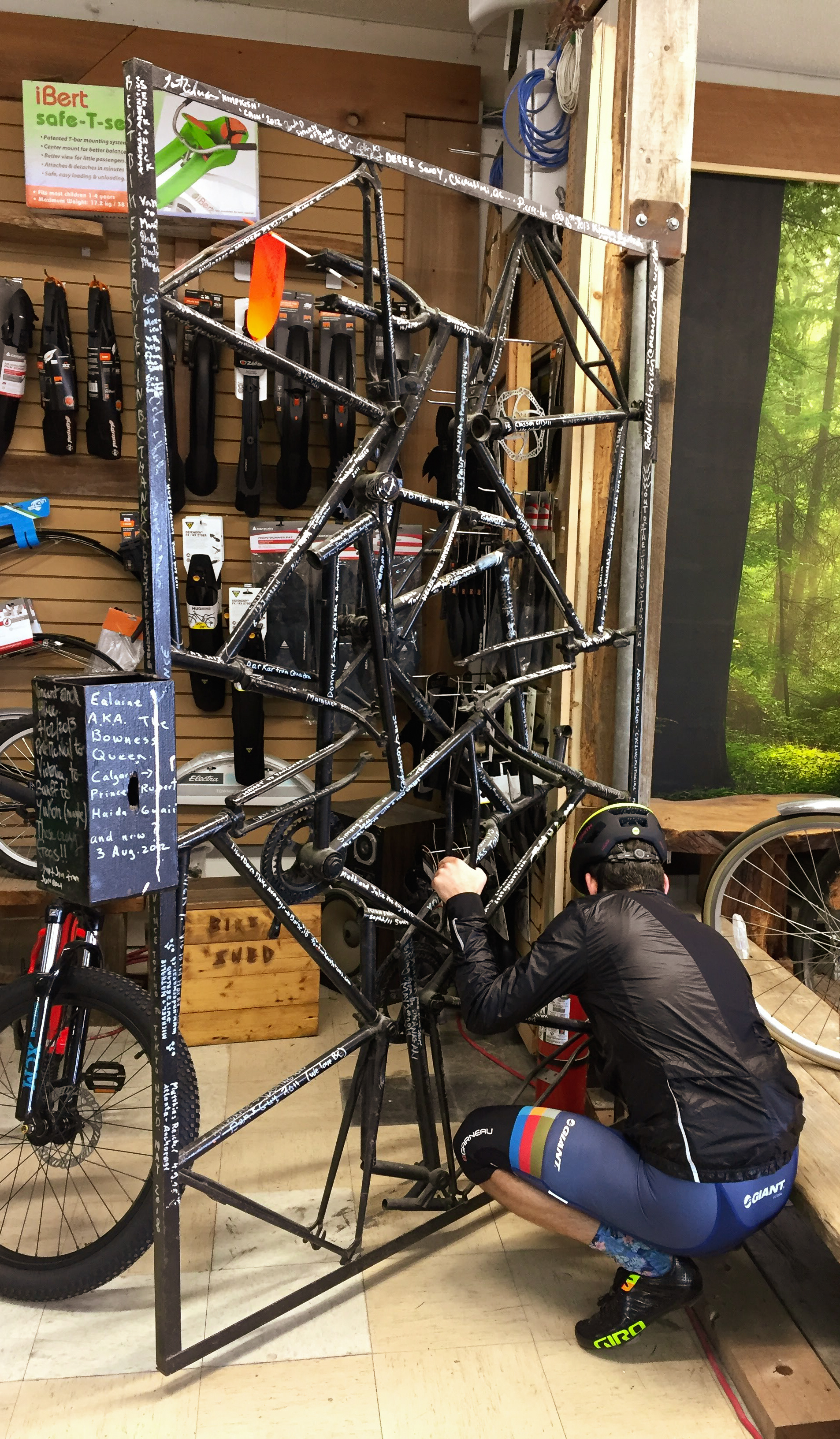 A mural of old bike frames welded together, covered in signatures.