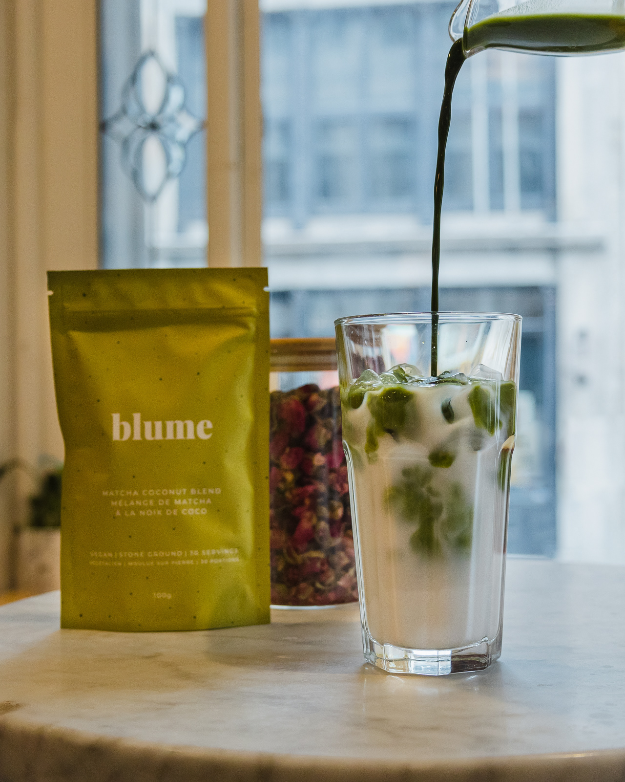 Matcha tea being poured in a glass of milk for a product photoshoot