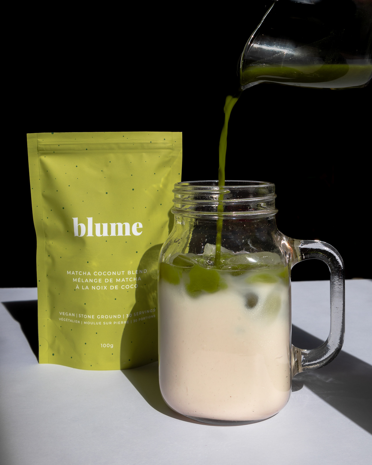 Matcha tea being poured in a glass of milk and a tea bag
