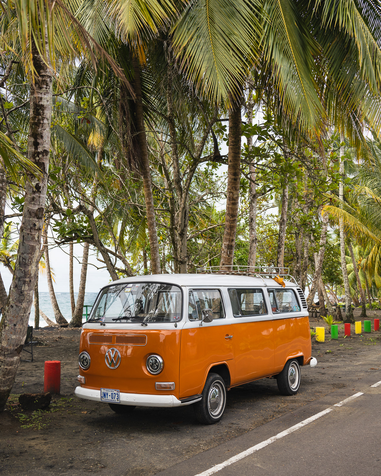 Orange Volkswagen Westfalia camper parked in front of palm trees in Costa Rica