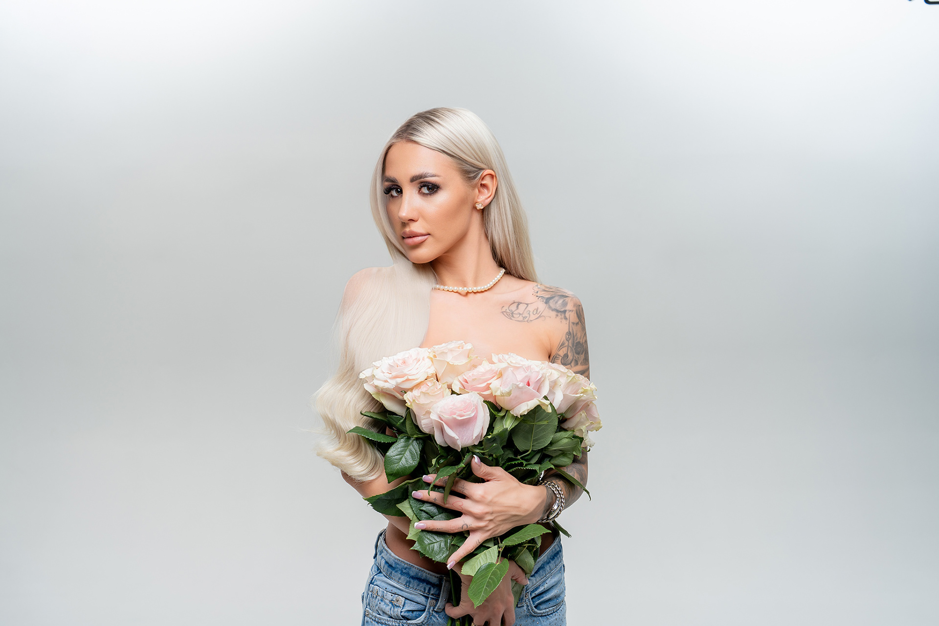 Елегантен портрет на Габи с дълга коса и нежен букет рози, излъчваща баланс между смелост и деликатност