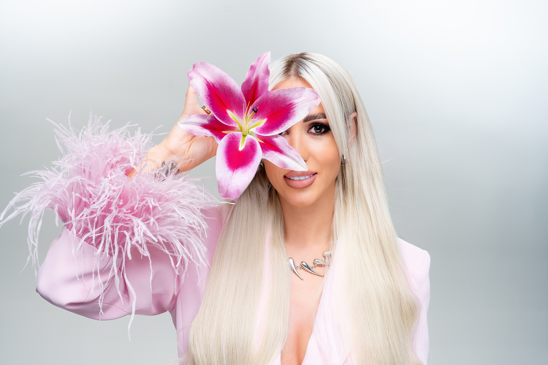 Портрет на Габи, облечена в розов костюм с пера, държаща лилия — символ на женственост и вдъхновение