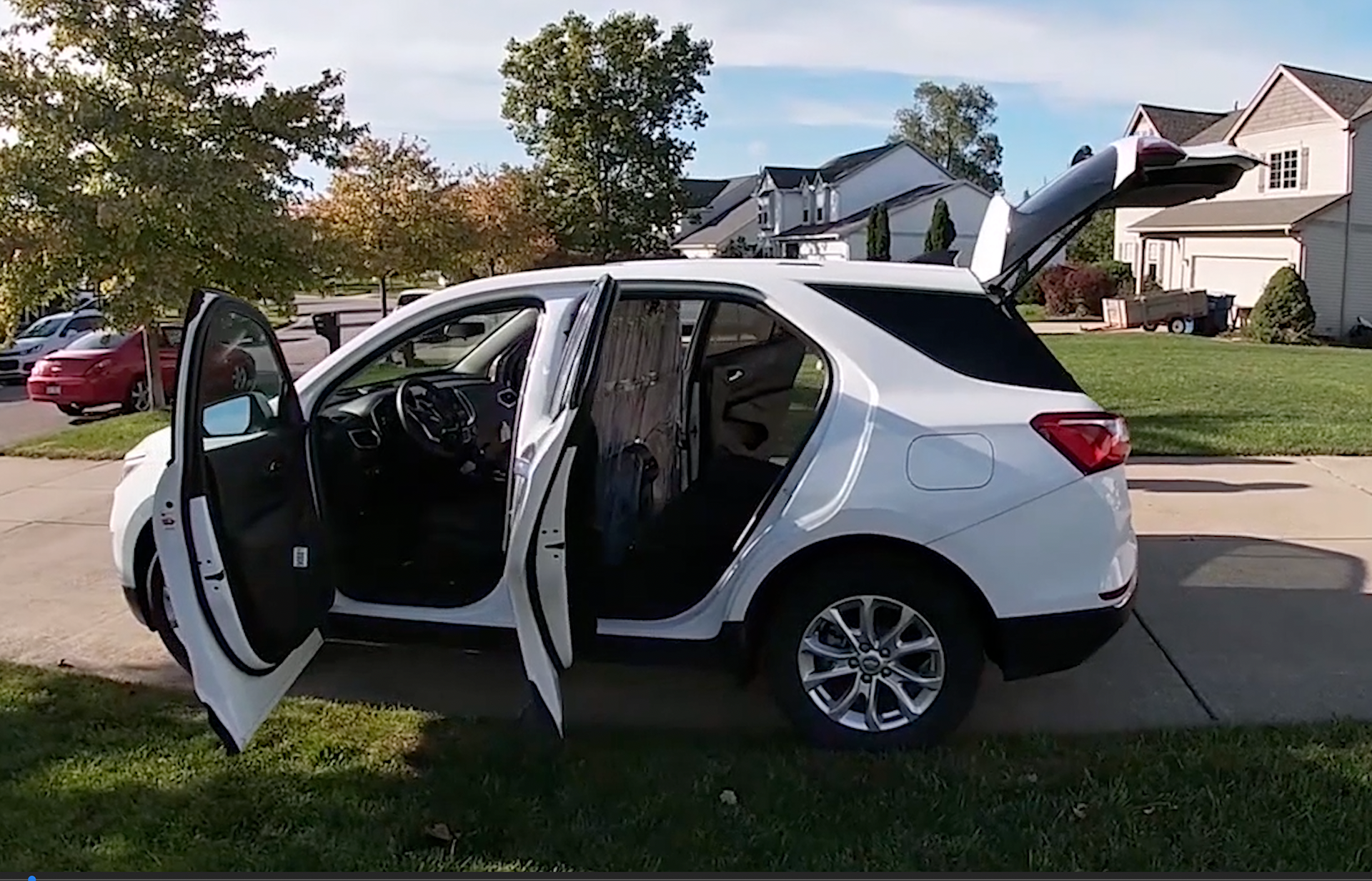 A white SUV parked in a driveway with all doors and hatch open.