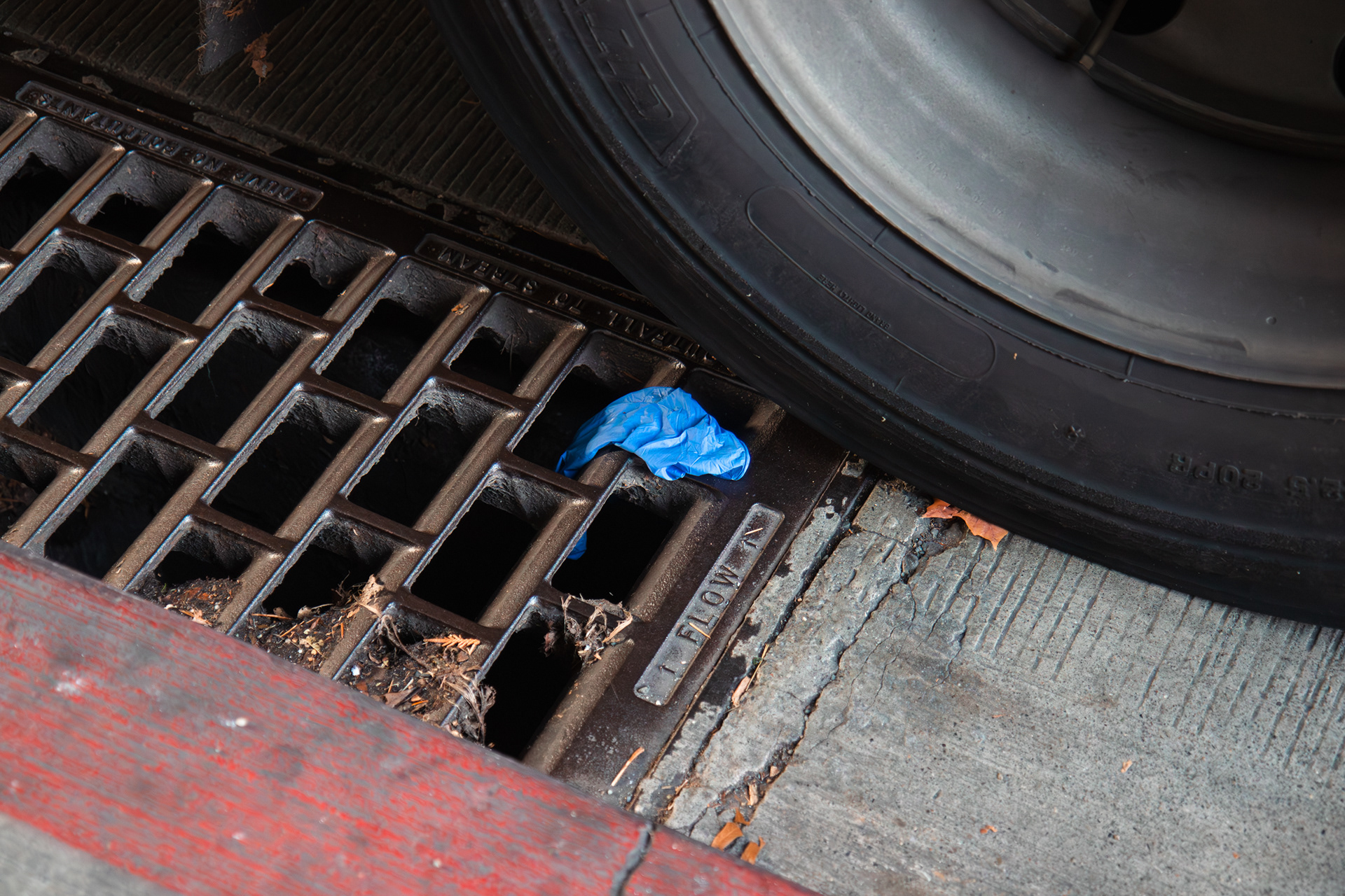 A blue glove is seen hanging above a sewer grate outside of the University of Washington Medical Center in Seattle, Wash. on Thursday, Oct. 26, 2023. As gloves are single-use, their usage has increased significantly, especially during the COVID-19 pandemic. (Photo by Chloe Sarmiento)