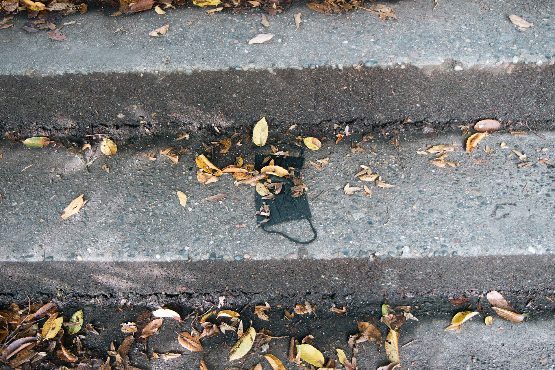 A black mask lays on the steps leading from the E18 parking lot at the University of Washington in Seattle, Wash. on Thursday, Oct.26, 2023. According to the Massachusetts Institute of Technology news in 2021, the COVID-19 pandemic was estimated to generate up to 7,200 tons of PPE waste every day, with a significant portion being medical masks. (Photo by Chloe Sarmiento)