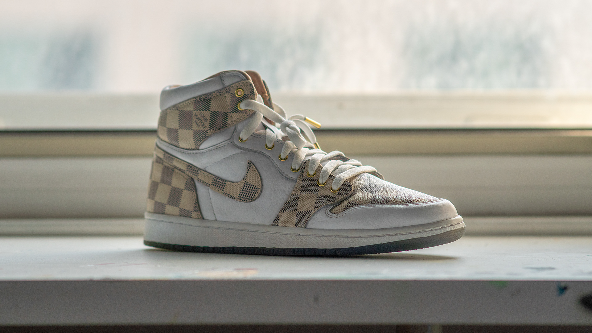 Nike Air Jordan 1 High, customized with Louis Vuitton Damier material, backlit by a big pane window