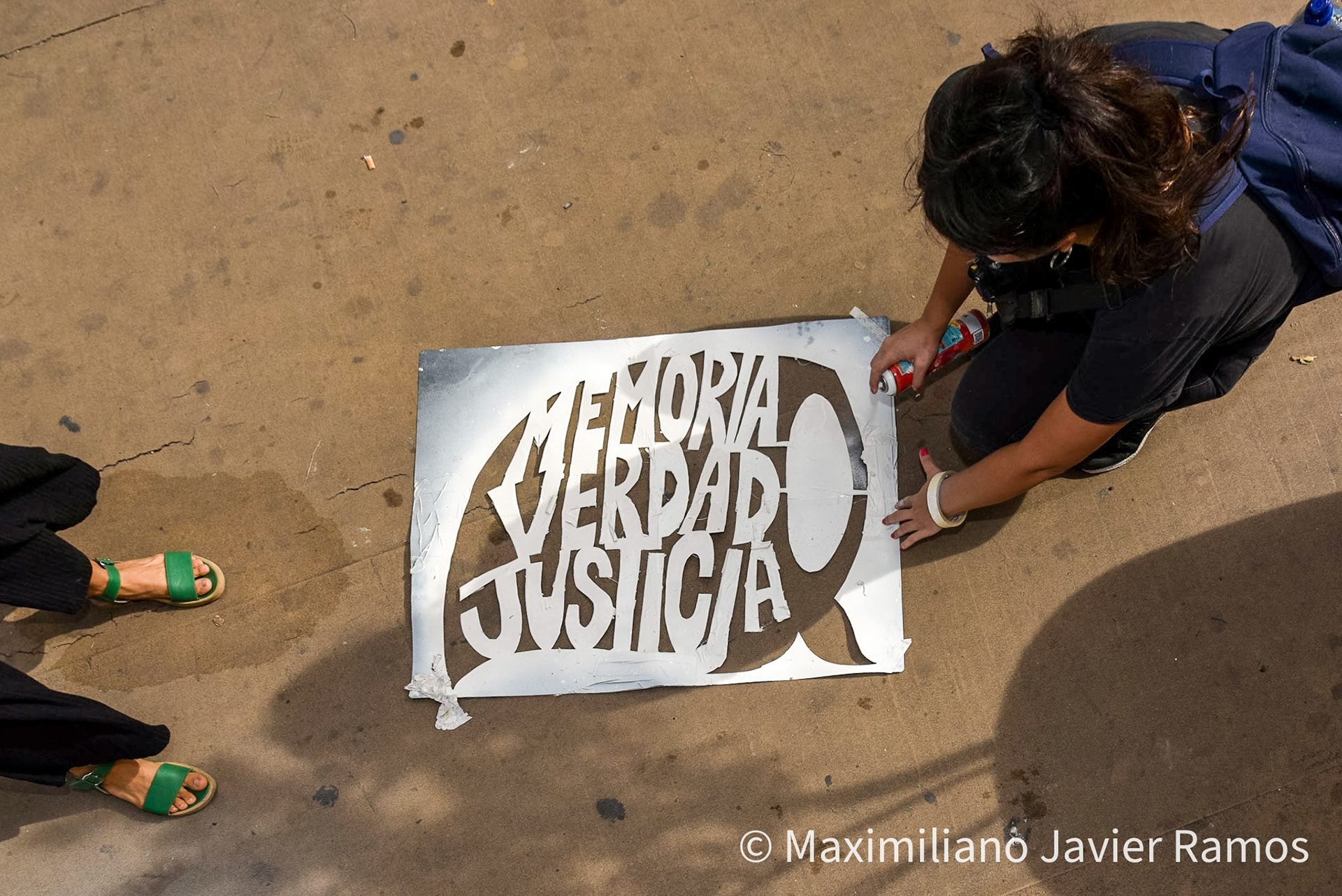 Dos mujeres preparan un graffiti con la consigna "Memoria, Verdad y Justicia” dentro de un pañuelo blanco, símbolo de las Abuelas de Plaza de Mayo, durante la marcha por el Día de la Memoria. / Two women prepare a graffiti with the slogan "Memory, Truth and Justice" inside a white handkerchief, symbol of the Grandmothers of Plaza de Mayo, during the march for Remembrance Day. / El Día Nacional de la Memoria por la Verdad y la Justicia es un día feriado inamovible de Argentina que se conmemora cada 24 de marzo. La fecha remite al golpe de Estado del 24 de marzo de 1976 y busca generar memoria y conciencia colectiva para que los golpes de Estado y las violaciones de derechos humanos no se repitan "nunca más" y sus autores sean enjuiciados y castigados. El Proceso de Reorganización Nacional fue una dictadura cívico-militar que causó que decenas de miles de personas fueran asesinadas, desaparecidas, violadas, torturadas, secuestradas siendo bebés, o debieran nacer en cautiverio, padecer la sustracción de su identidad y sufrir el exilio. Las organizaciones de derechos humanos, los sindicatos, el movimiento estudiantil, los movimientos sociales y muchos partidos políticos hacen referencia a los 30 000 desaparecidos,1 que fueron víctimas de la última dictadura y cuya presencia en la sociedad actual se invoca en cada conmemoración al grito “30.000 detenidos-desaparecidos ¡Presentes! ¡Ahora y siempre!” / The National Day of Memory for Truth and Justice is an immovable holiday in Argentina that is commemorated every March 24. The date refers to the coup d'état of March 24, 1976 and seeks to generate memory and collective awareness so that coups d'état and human rights violations are not repeated "never again" and their perpetrators are prosecuted and punished. The National Reorganization Process was a civil-military dictatorship that caused tens of thousands of people to be killed, disappeared, raped, tortured, kidnapped as babies, or had to be born in captivity, suffer theft of their identity and suffer exile. Human rights organizations, trade unions, the student movement, social movements and many political parties refer to the 30,000 disappeared,1 who were victims of the last dictatorship and whose presence in today's society is invoked in every shouted commemoration “30,000 detained-disappeared Present! Now and always!"